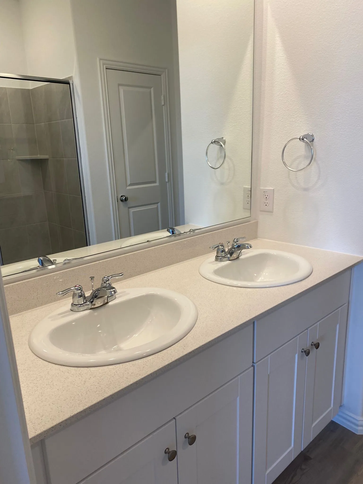 Double vanity with undermount sinks, chrome fixtures, and light-toned solid surface countertop