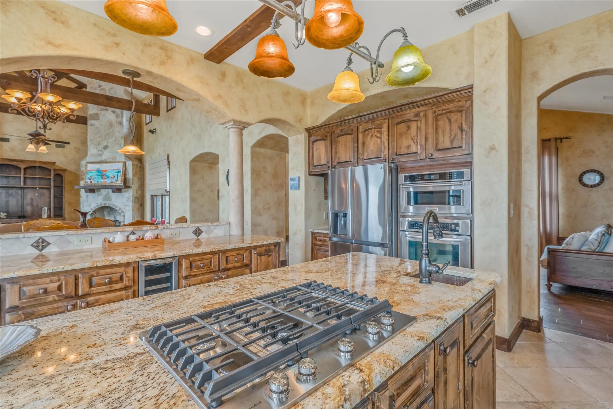Kitchen featuring granite countertops, built-in stainless steel appliances, a gas cooktop, dark wood cabinetry, and an integrated beverage refrigerator