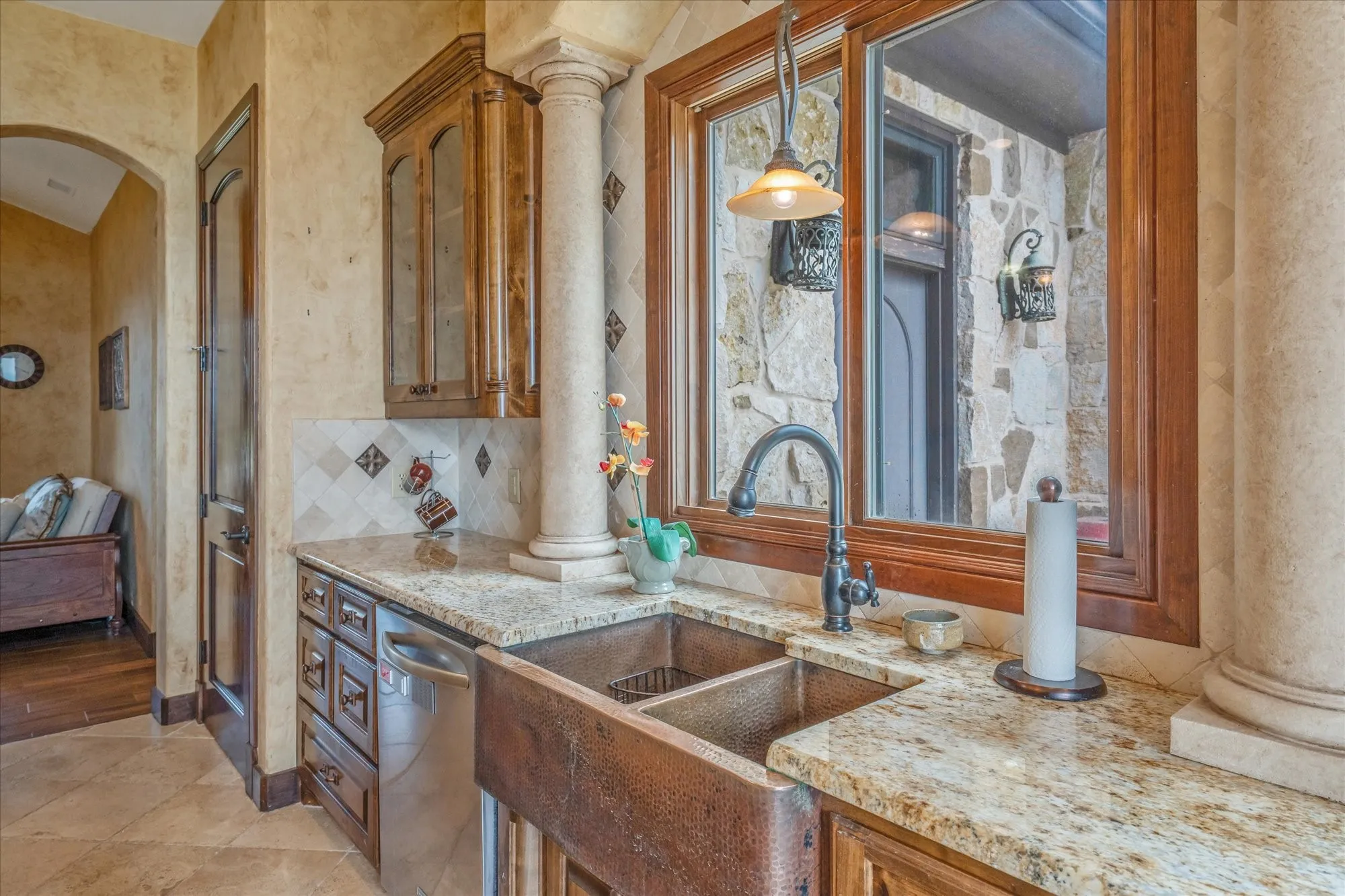 Granite countertop with a copper farmhouse sink, featuring dark wood cabinetry and a stainless steel dishwasher