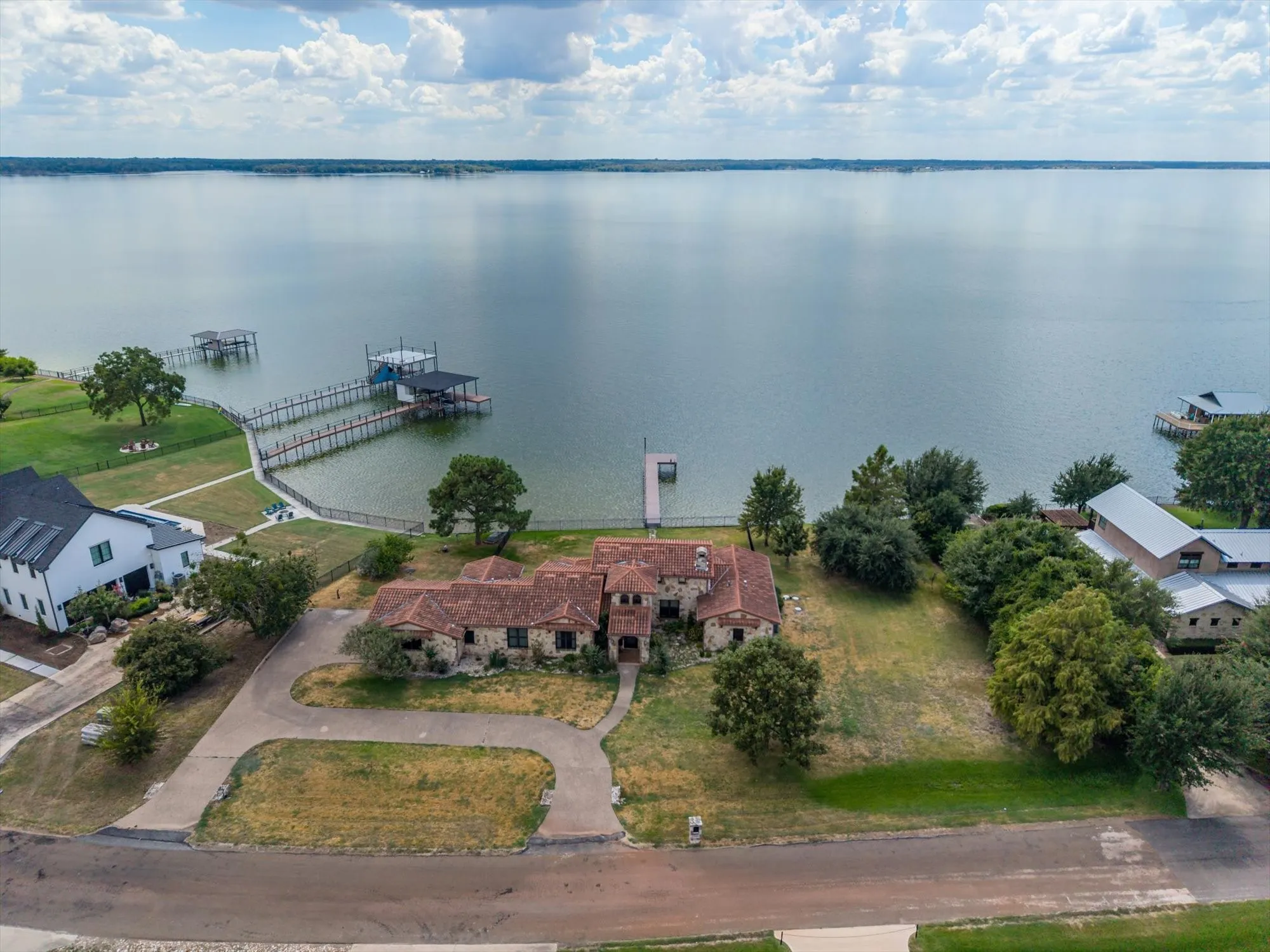 Expansive waterfront property featuring a stone and tile-roof residence, private boat dock with covered slip, and a large body of water