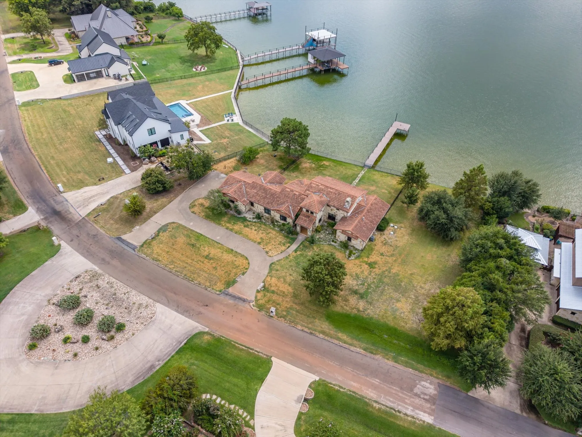 Waterfront property featuring a private dock, expansive grounds, and a circular driveway