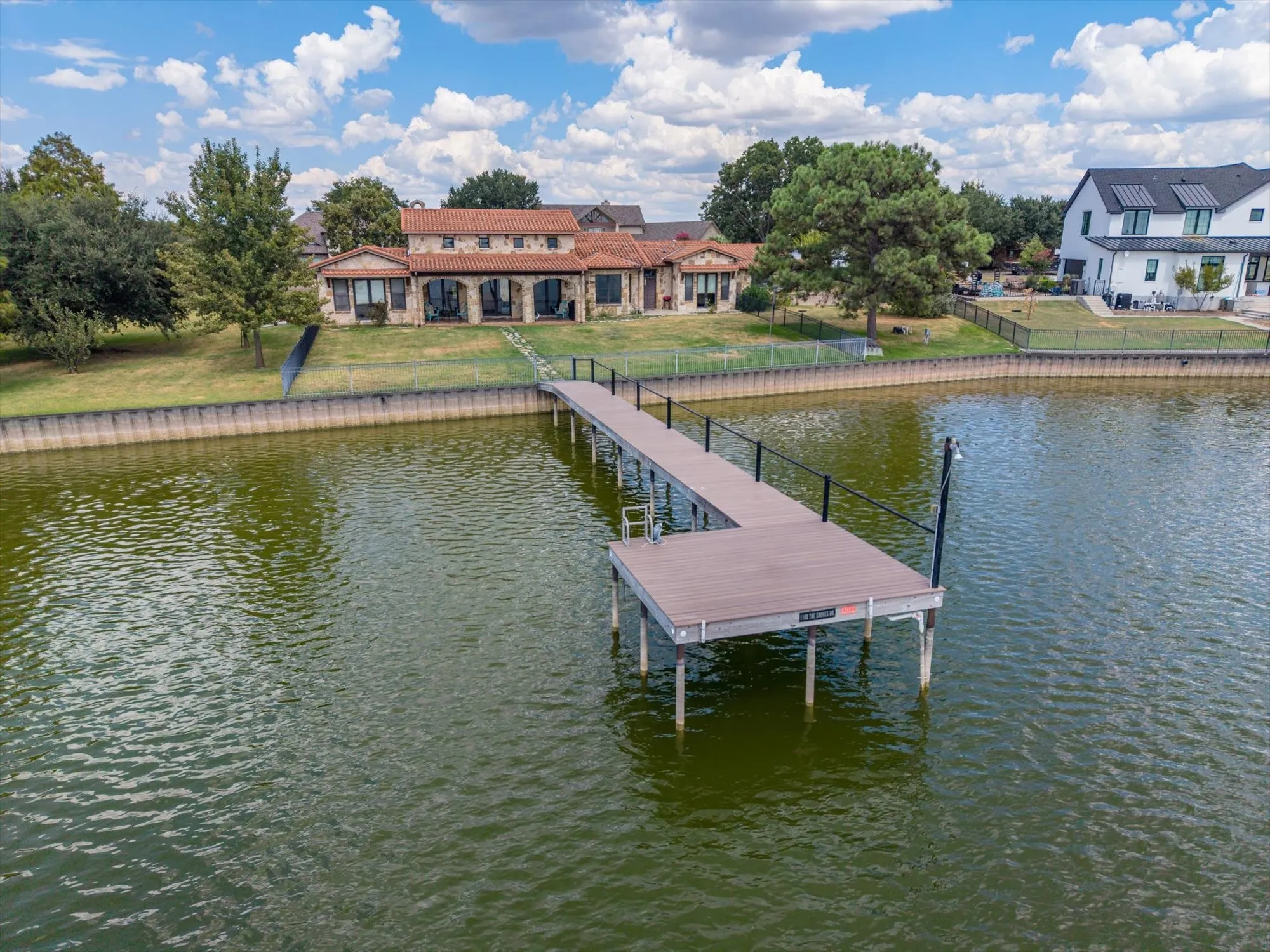 Lakefront property featuring a stone exterior, terracotta roof, and a private dock
