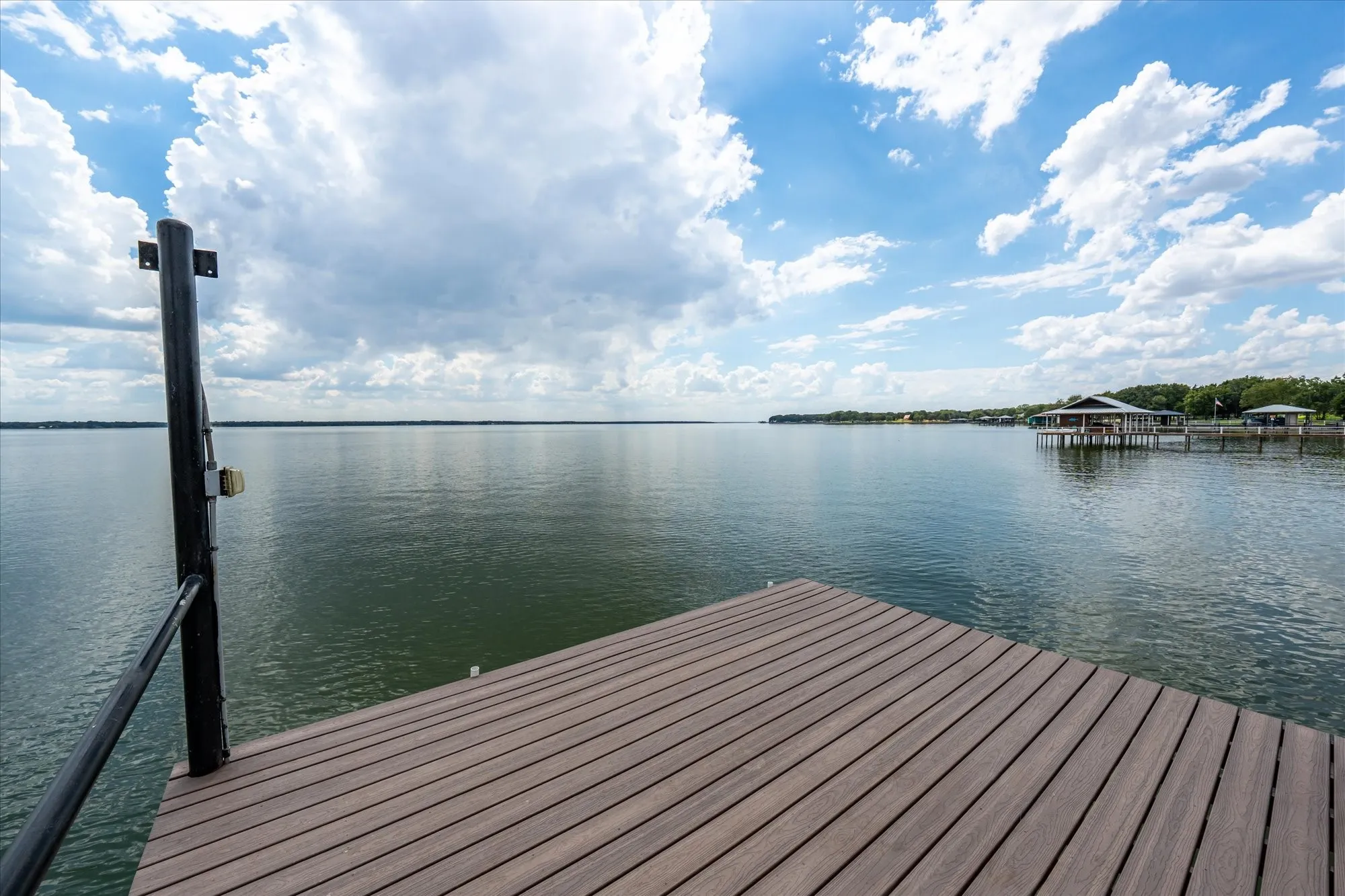 Dock with composite decking and black metal railing, extending over expansive water