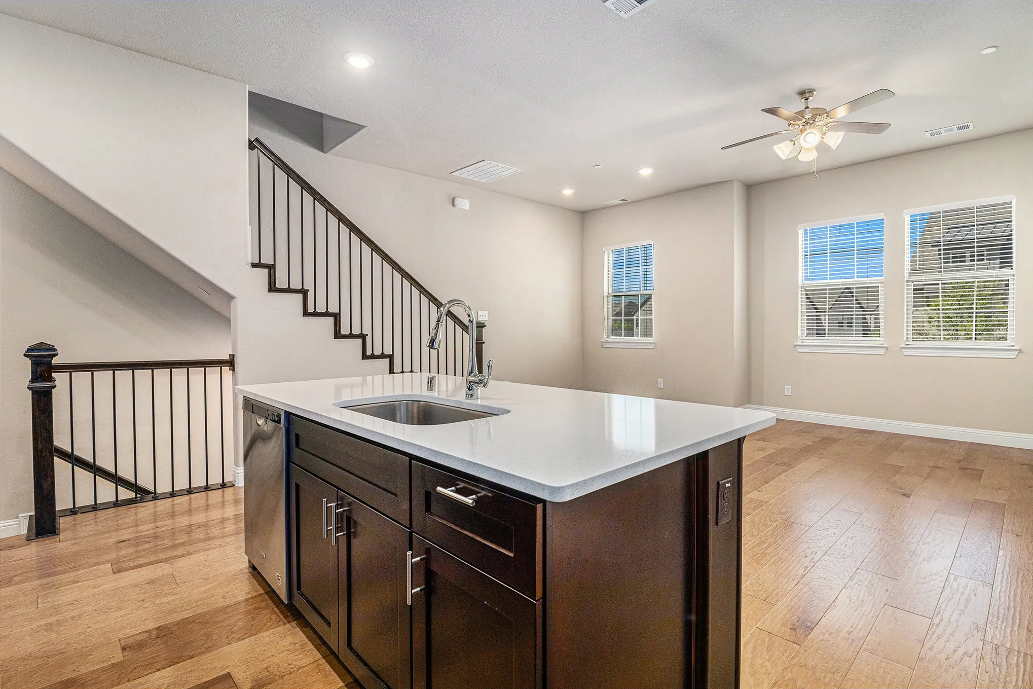 Kitchen island with a stainless steel sink, a stainless steel dishwasher, and dark wood-finish cabinetry