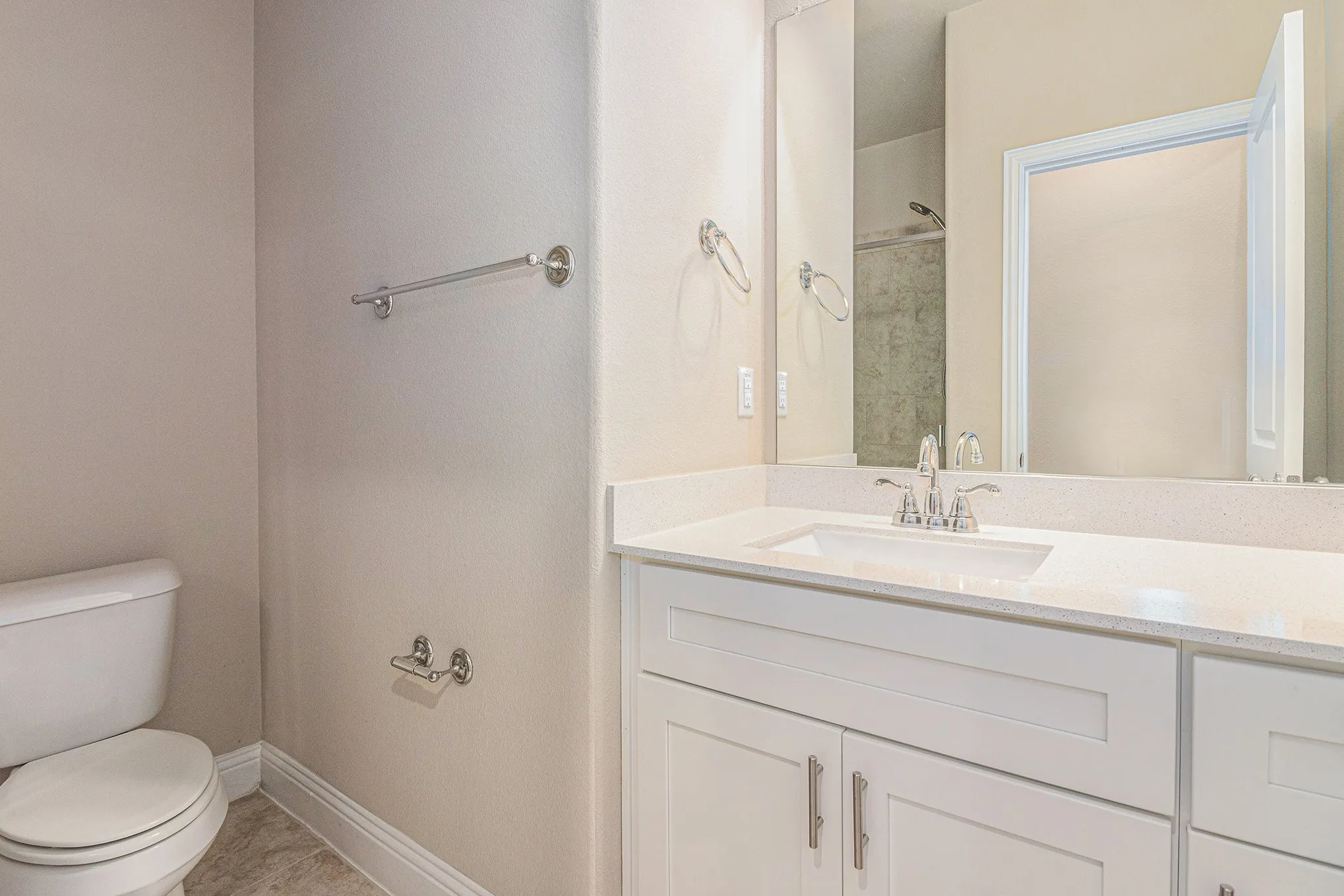 White vanity with a neutral countertop, undermount sink, and chrome faucet