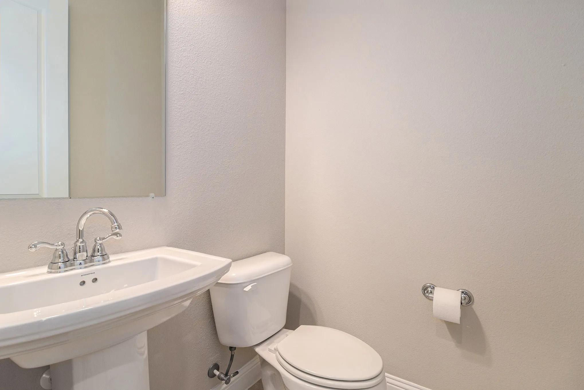 Pedestal sink with chrome fixtures and a rectangular mirror