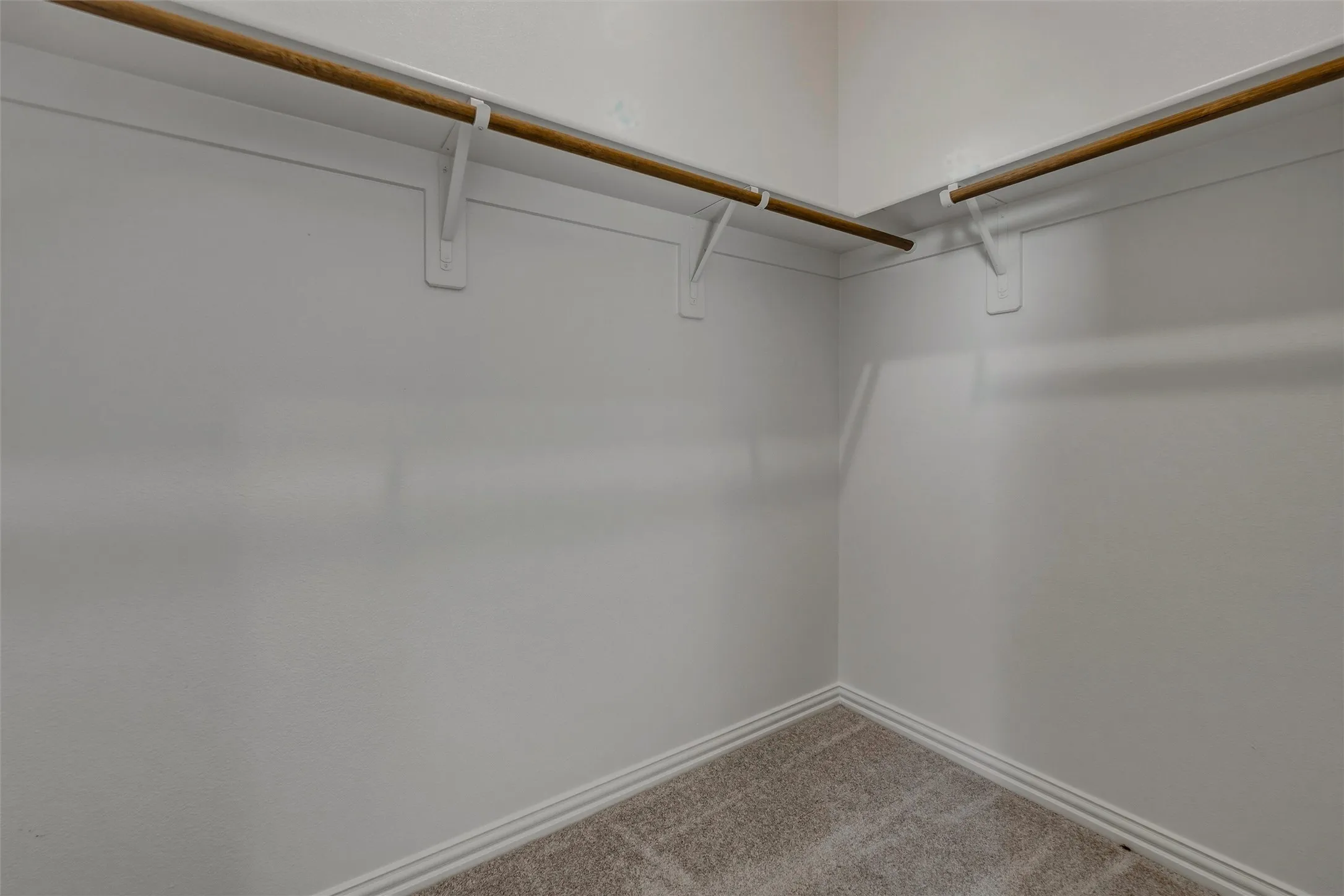 Corner closet with built-in hanging rods and light-toned carpeting