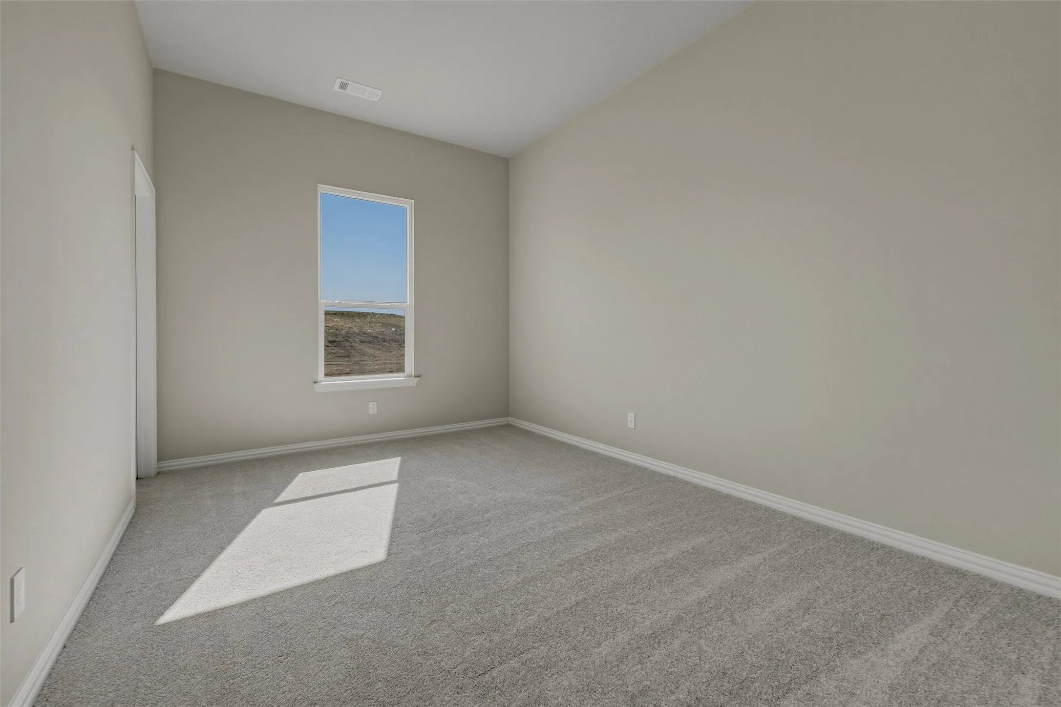 Carpeted interior space with a vaulted ceiling and a single window