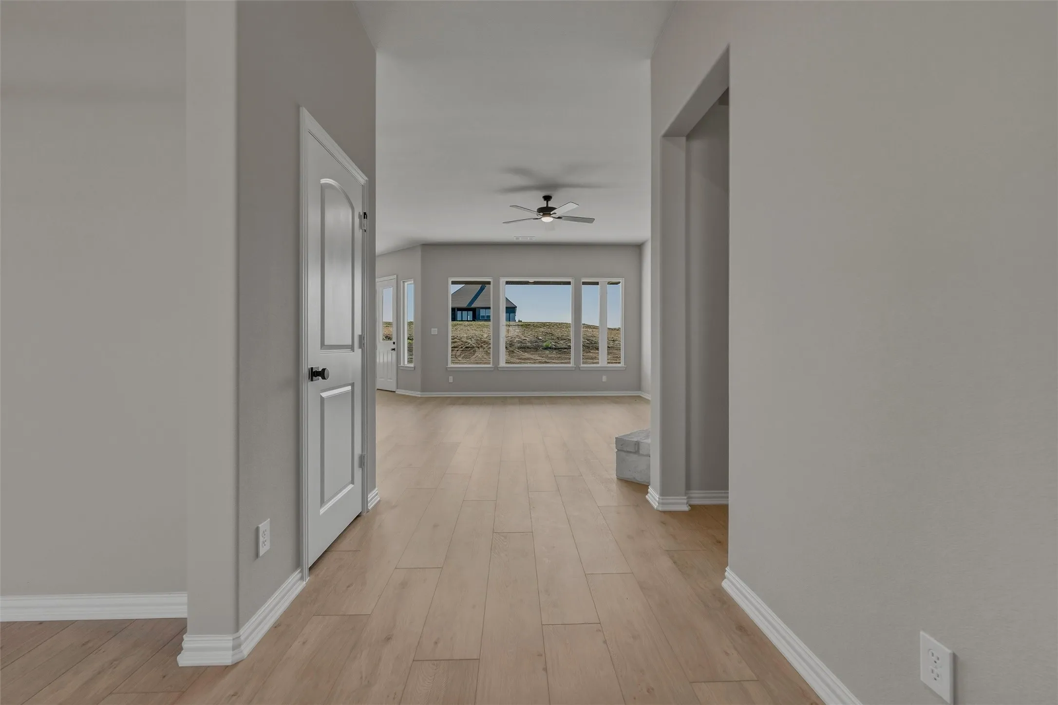 Wood-finish flooring throughout, bright interior paint, multiple windows, and a ceiling fan