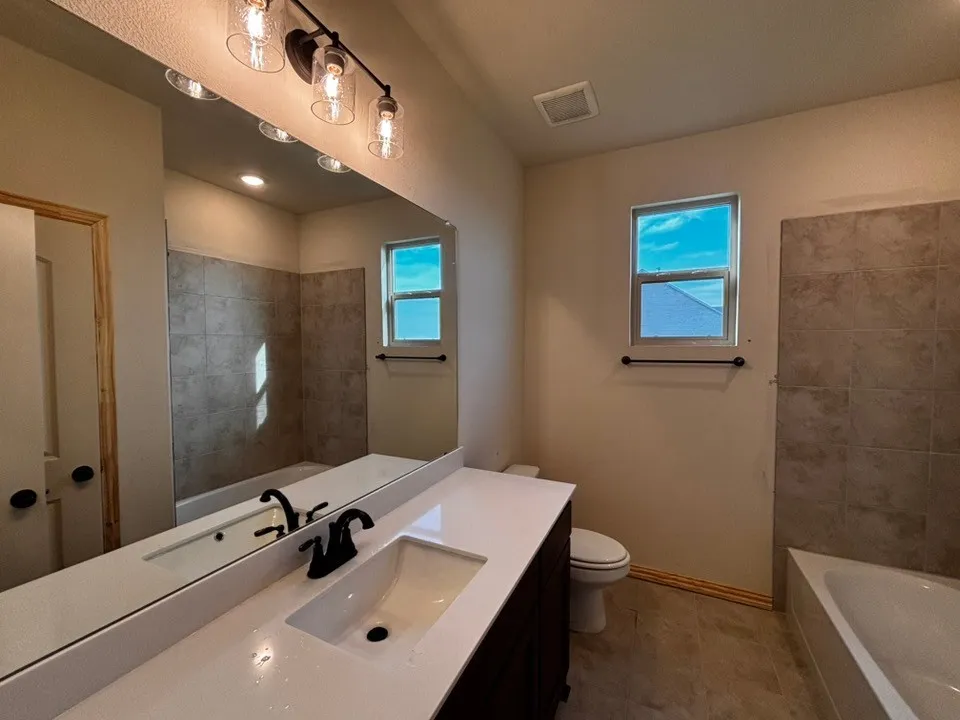 Bathroom featuring a white vanity countertop, undermount sink with a matte black faucet, dark wood-finish cabinetry, and a full-width mirror