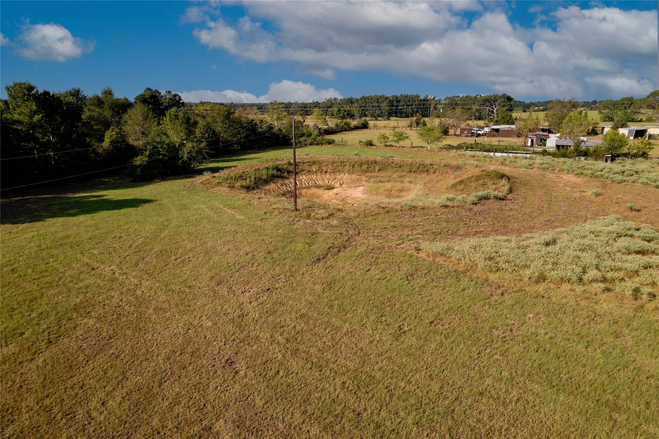Expansive open terrain with varied natural growth and distant structures