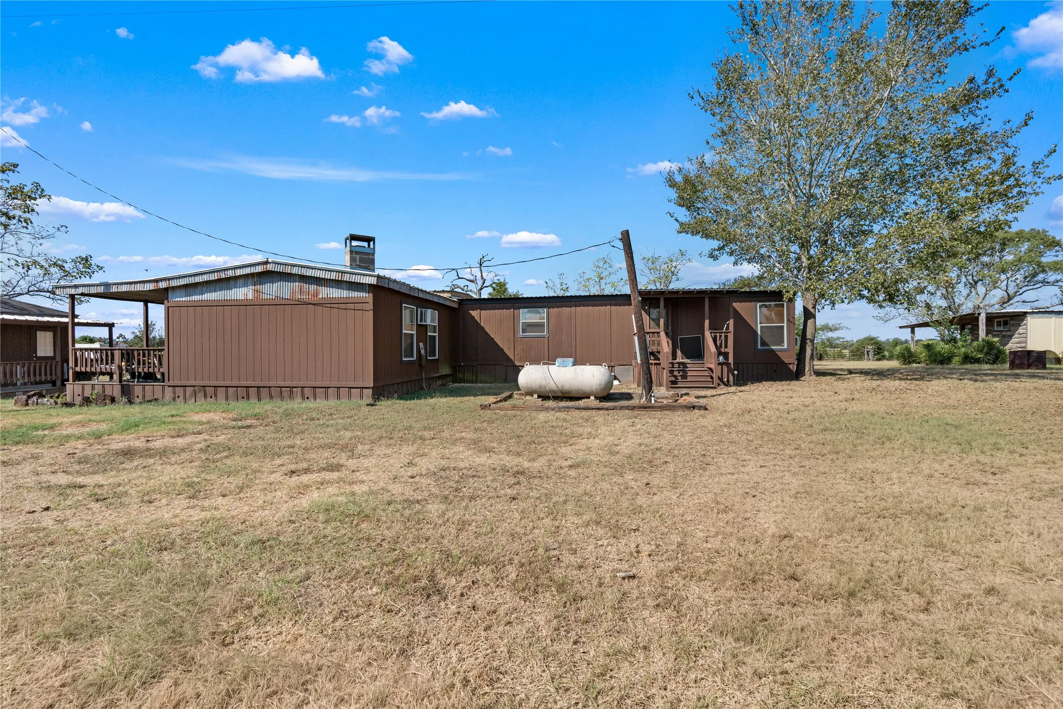 Expansive lot featuring a single-story residence with a covered porch and detached storage building