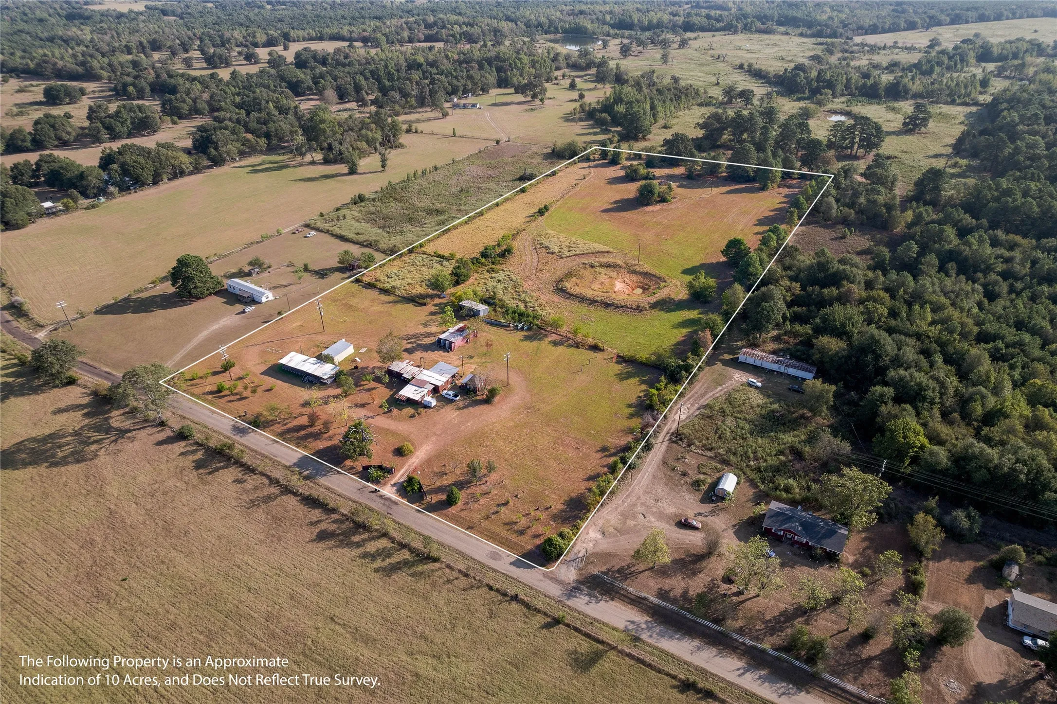 Expansive rural property featuring a defined boundary, multiple structures, a pond, open fields, and wooded areas