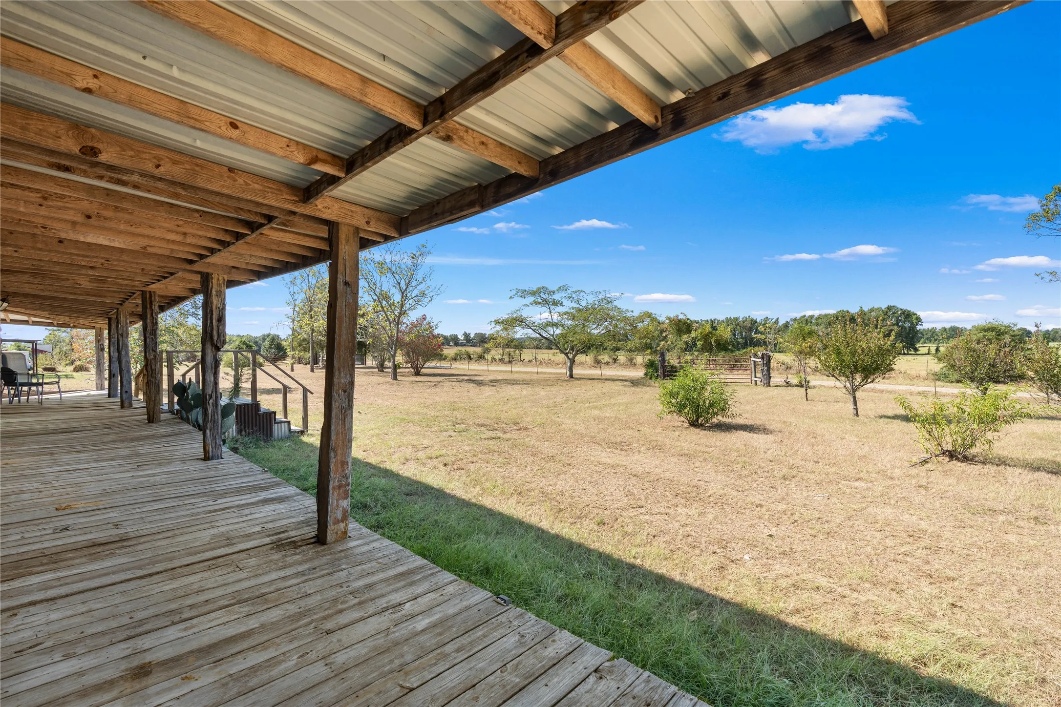 Expansive covered porch featuring a wood deck and exposed wood beams