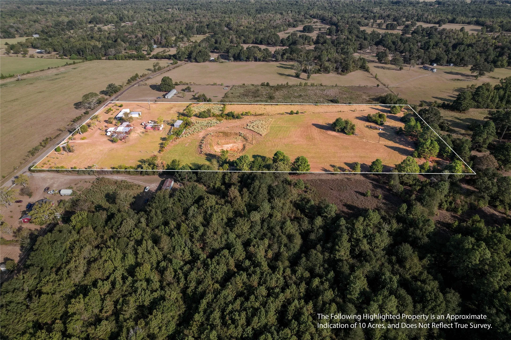 Expansive acreage featuring multiple structures, open fields, and mature trees