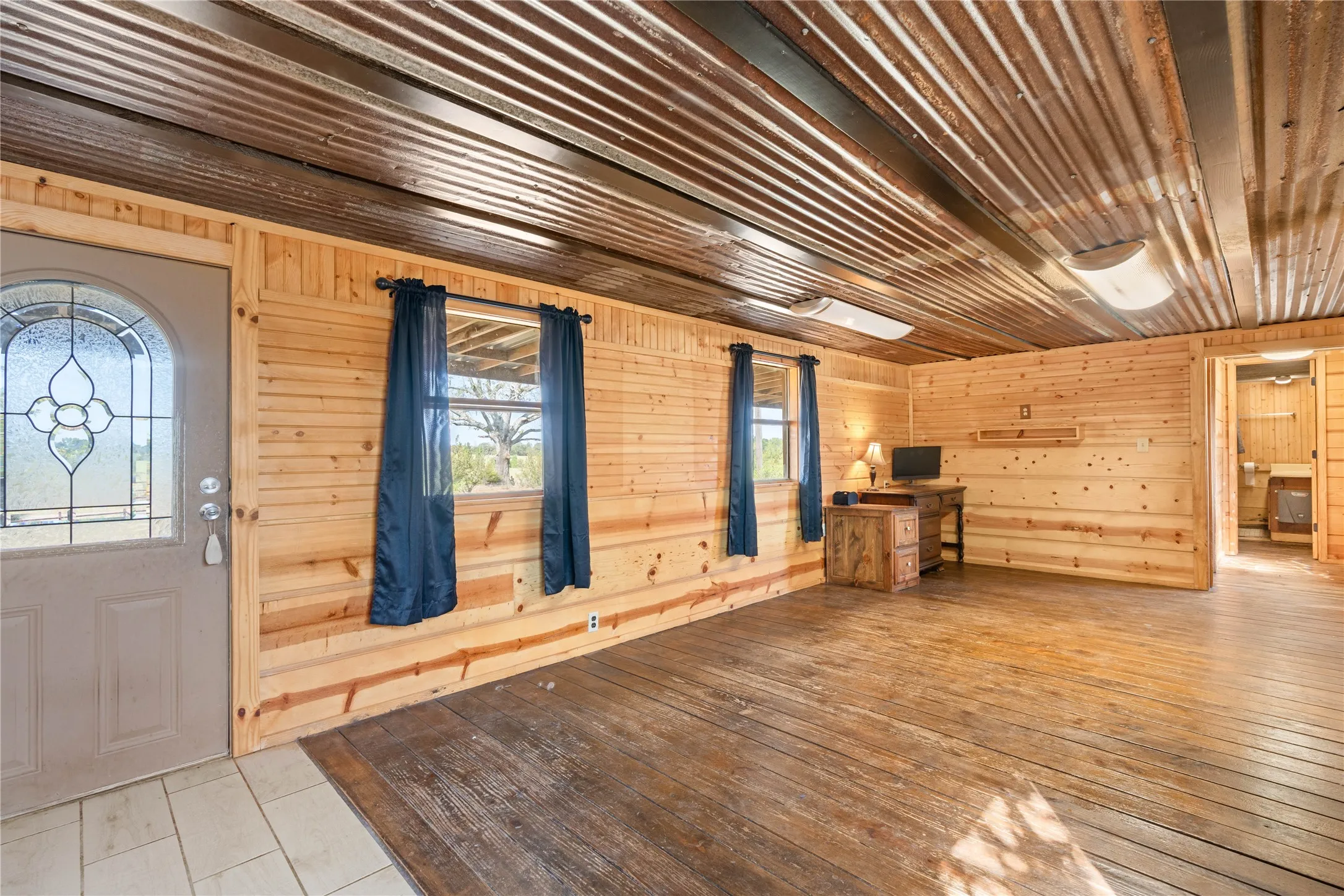 Wood-paneled interior walls, corrugated metal ceiling, and wood-finish flooring