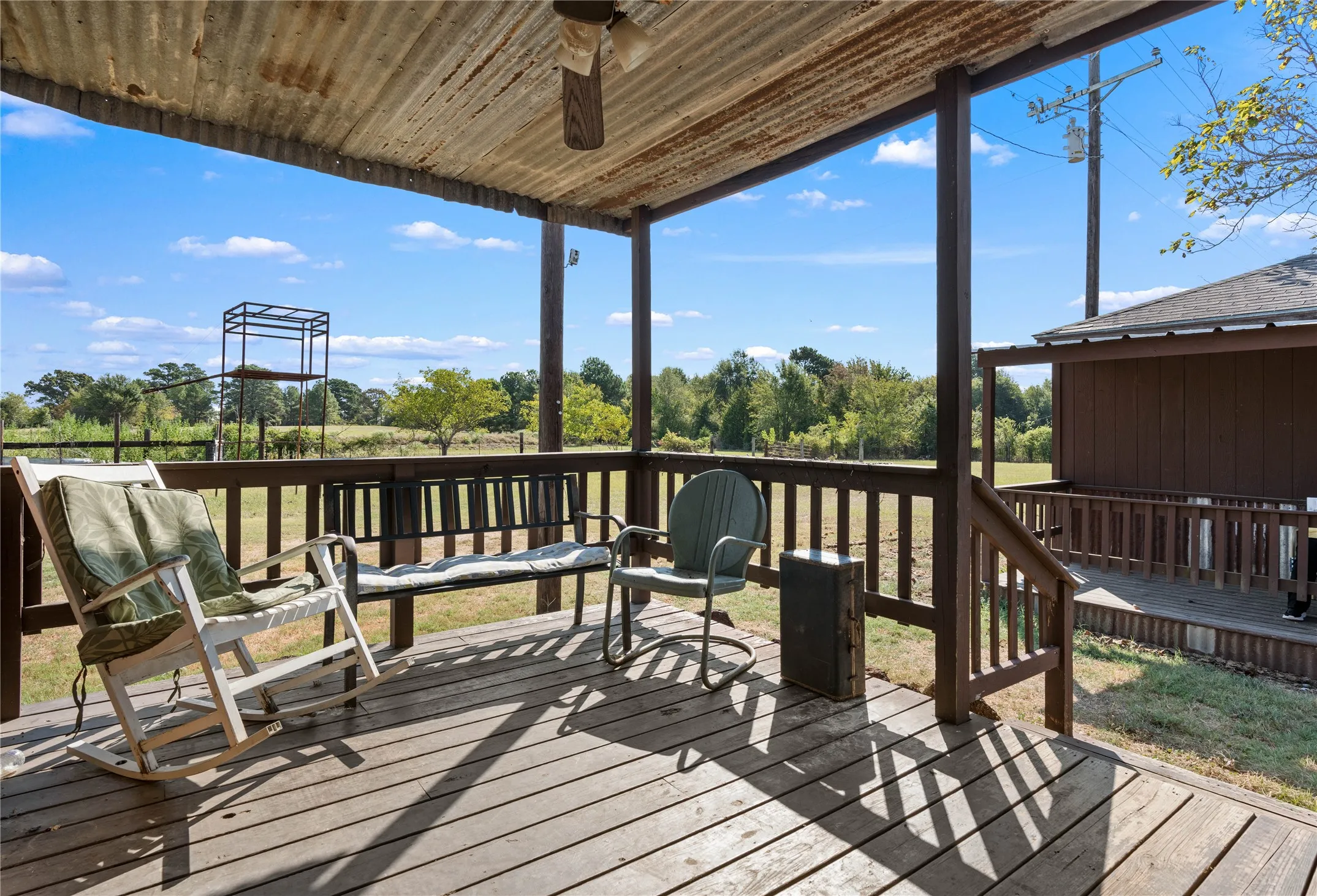 Covered wood-plank deck with a corrugated metal ceiling and wood railing