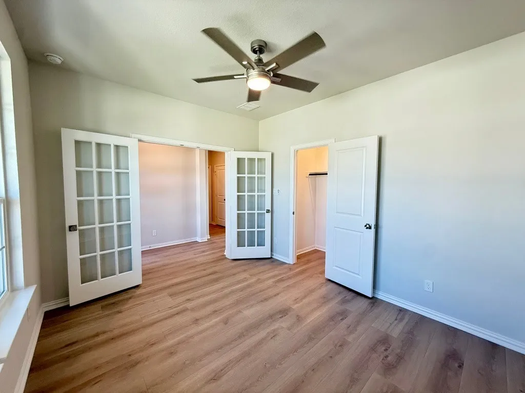 Wood-finish flooring, white French doors, recessed lighting, ceiling fan, and white trim