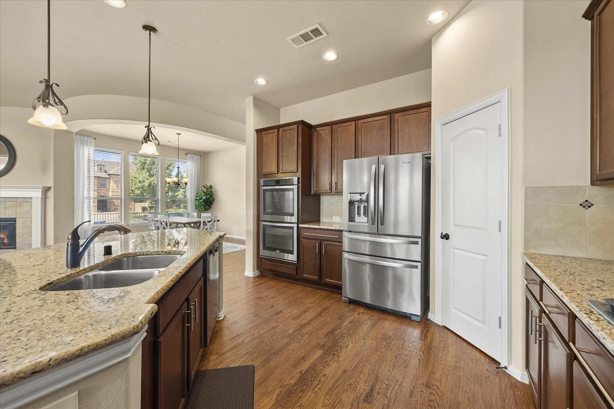 Kitchen featuring wood-finish flooring, dark wood cabinetry, stainless steel appliances, and light-toned countertops