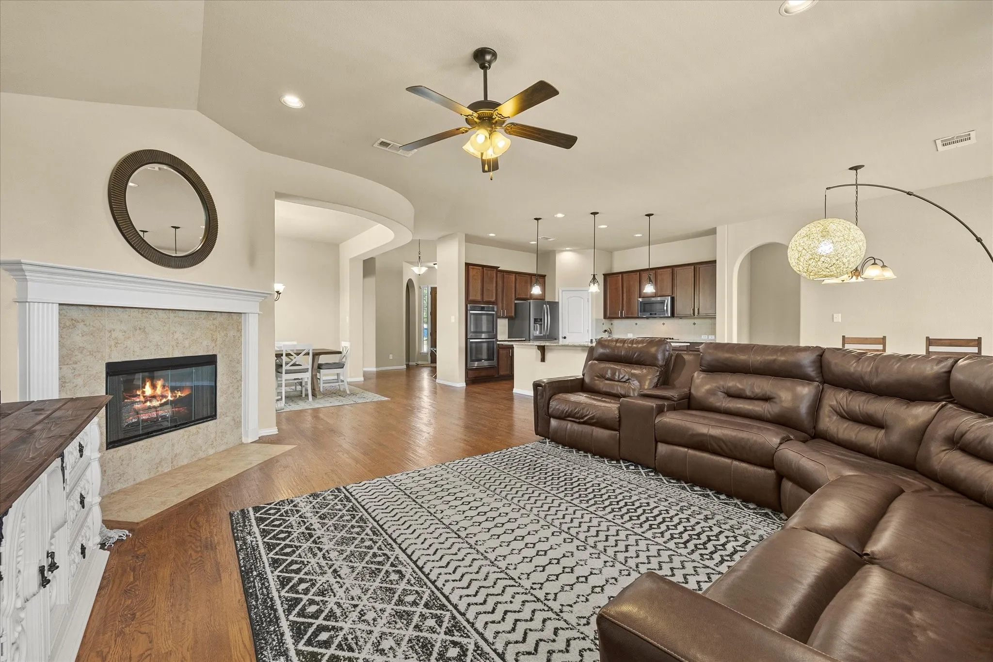 Hardwood-finish flooring throughout, a tile-surround fireplace with a classic mantel, and an open-concept layout