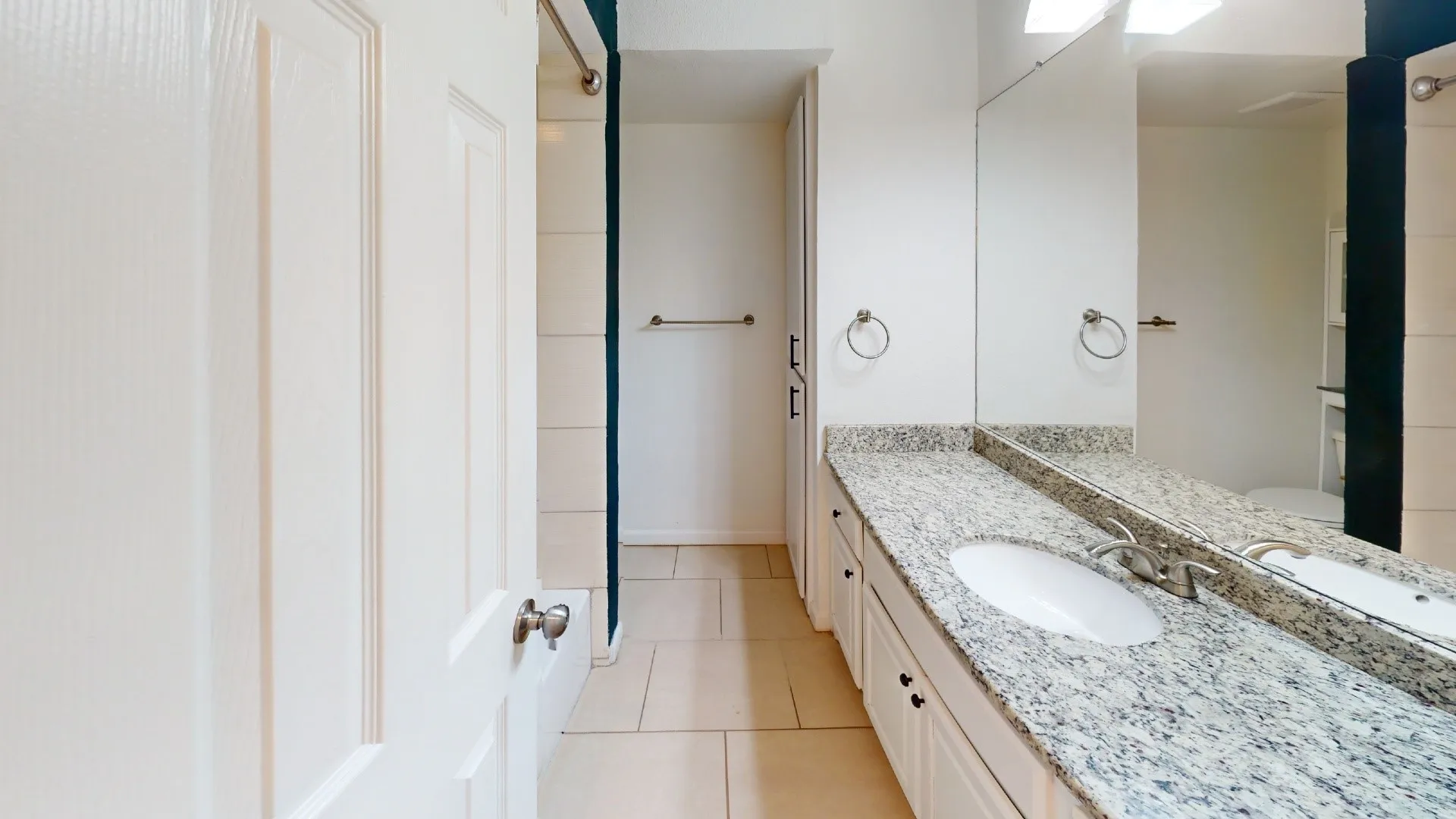 Double vanity with granite-style countertop, dual undermount sinks, and full-width mirror