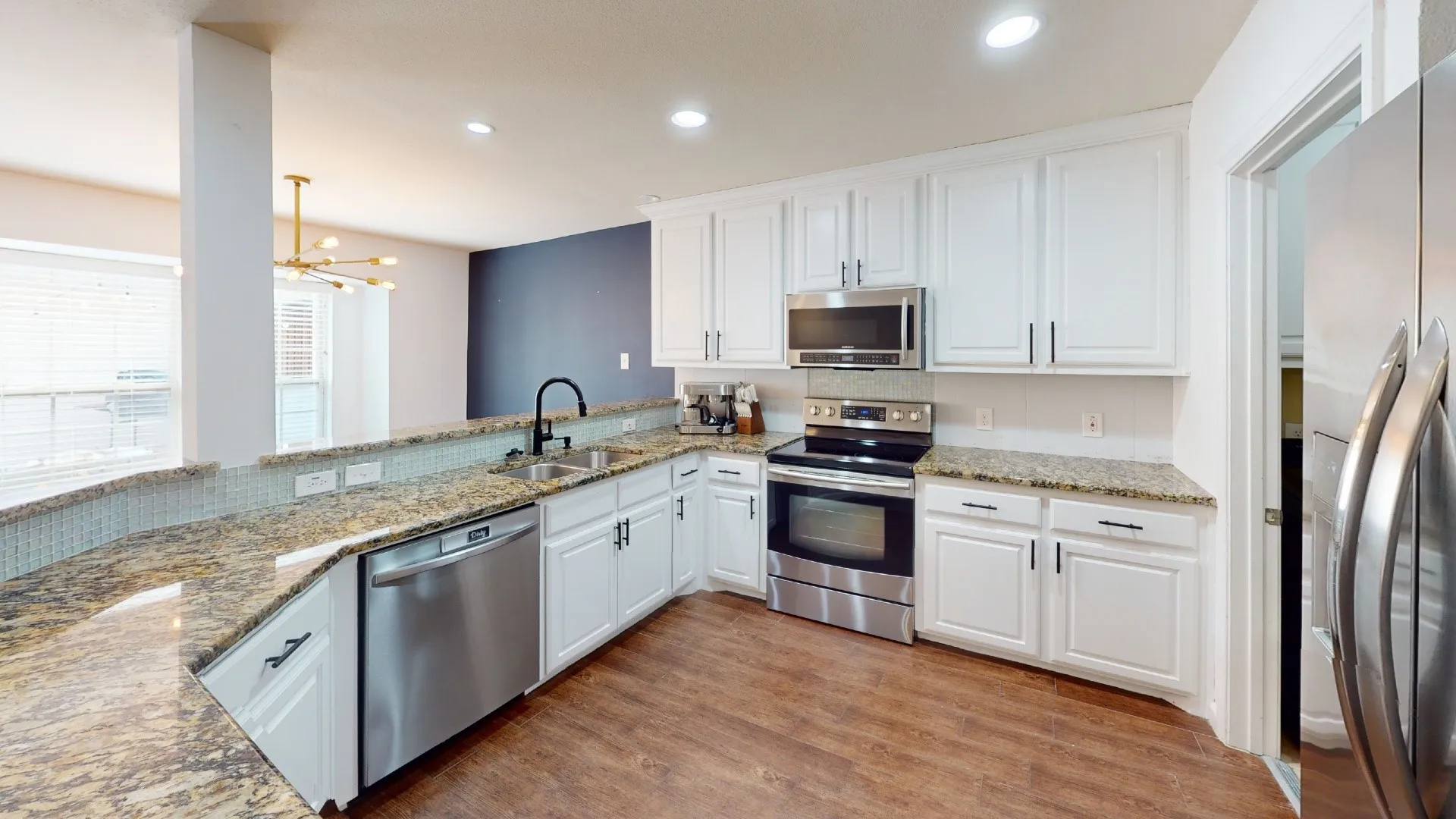 Kitchen featuring white cabinetry, stainless steel appliances, granite countertops, and wood-finish flooring