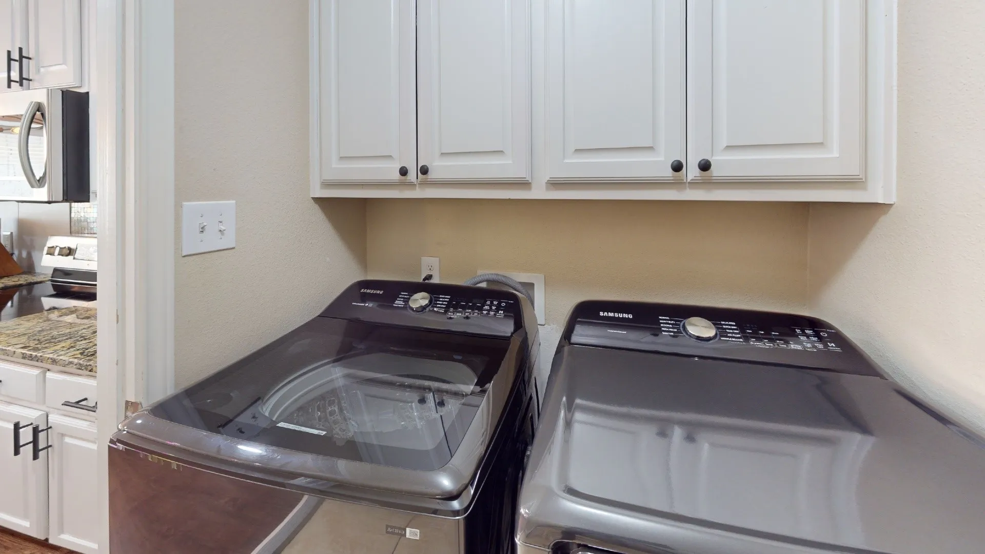 Laundry area with built-in white cabinetry and black hardware