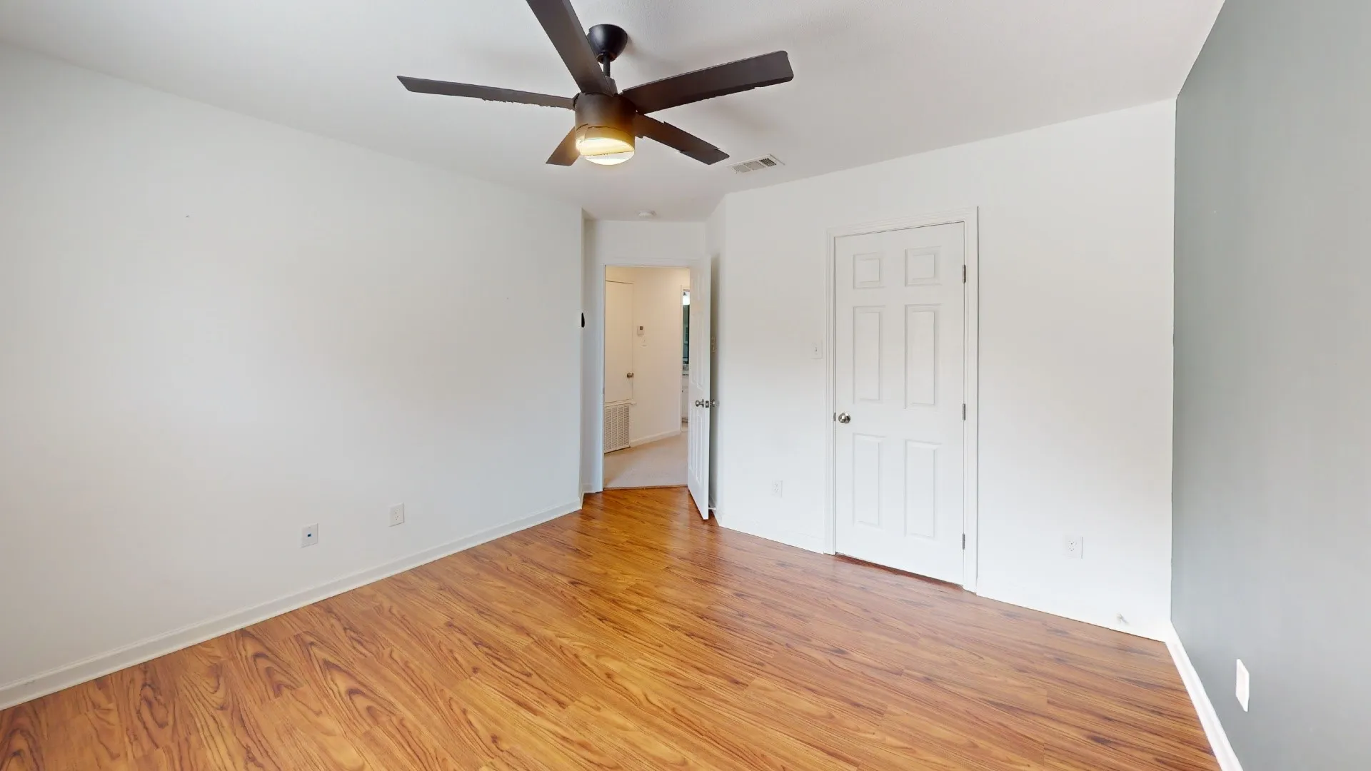 Wood-finish flooring, ceiling fan with integrated lighting, paneled interior doors, and contrasting wall colors