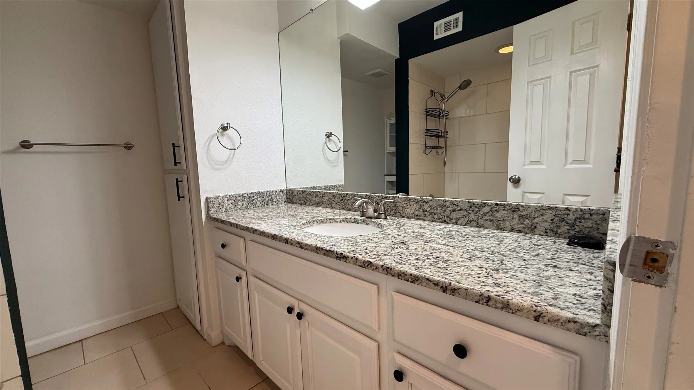 White vanity with dark hardware, a single integrated sink, and granite-finish countertop