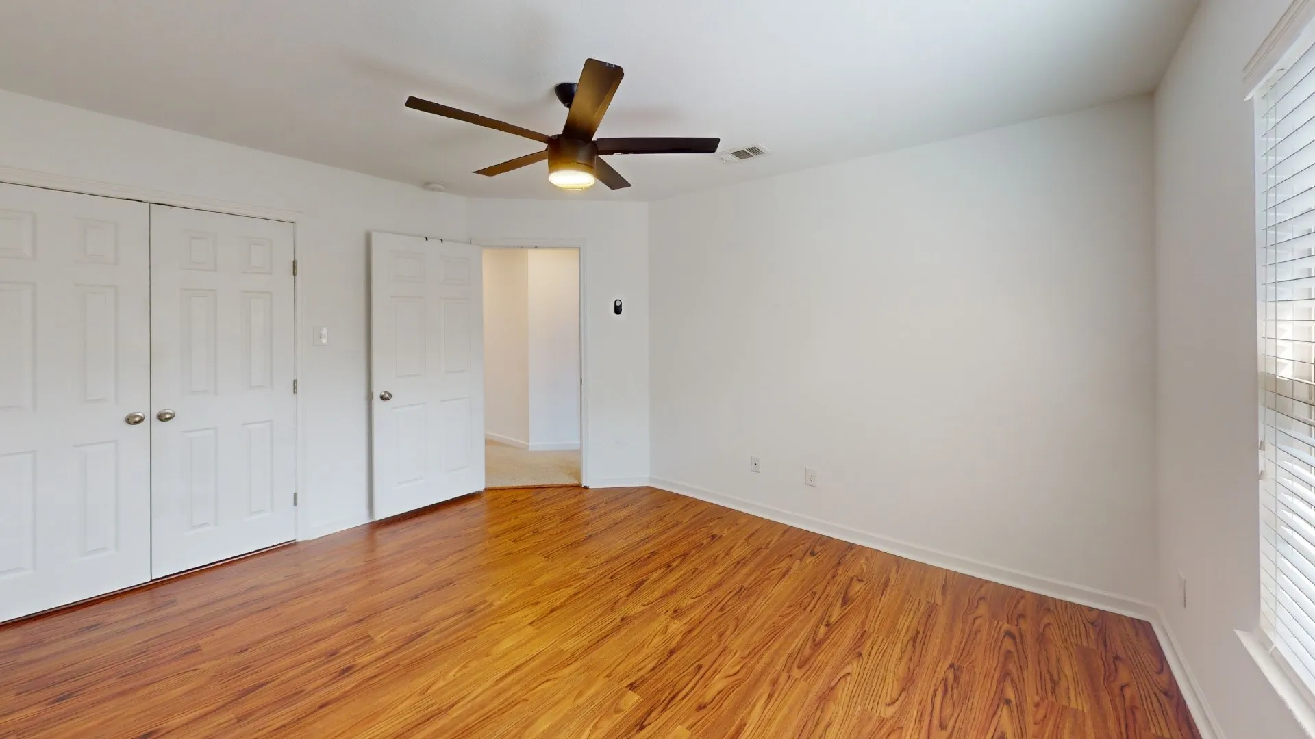 Wood-finish flooring, white walls, and a ceiling fan with integrated lighting