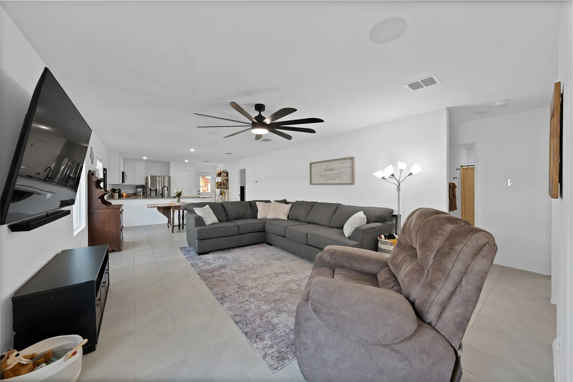 Open-concept living area with light-toned tile flooring, recessed lighting, and a ceiling fan