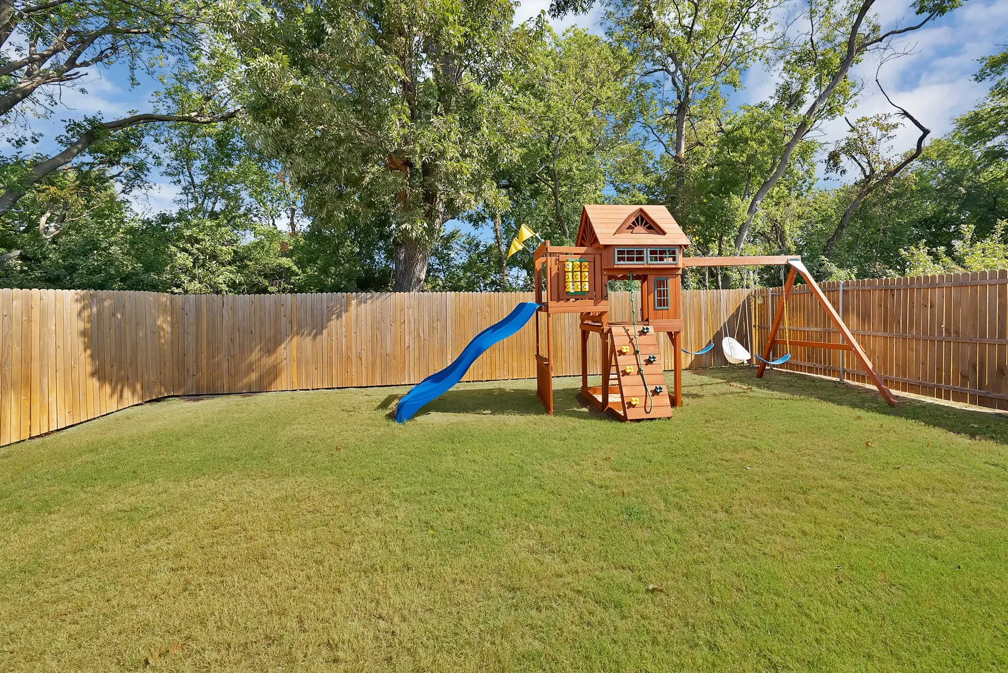 Expansive fenced backyard featuring a grassy lawn and mature trees