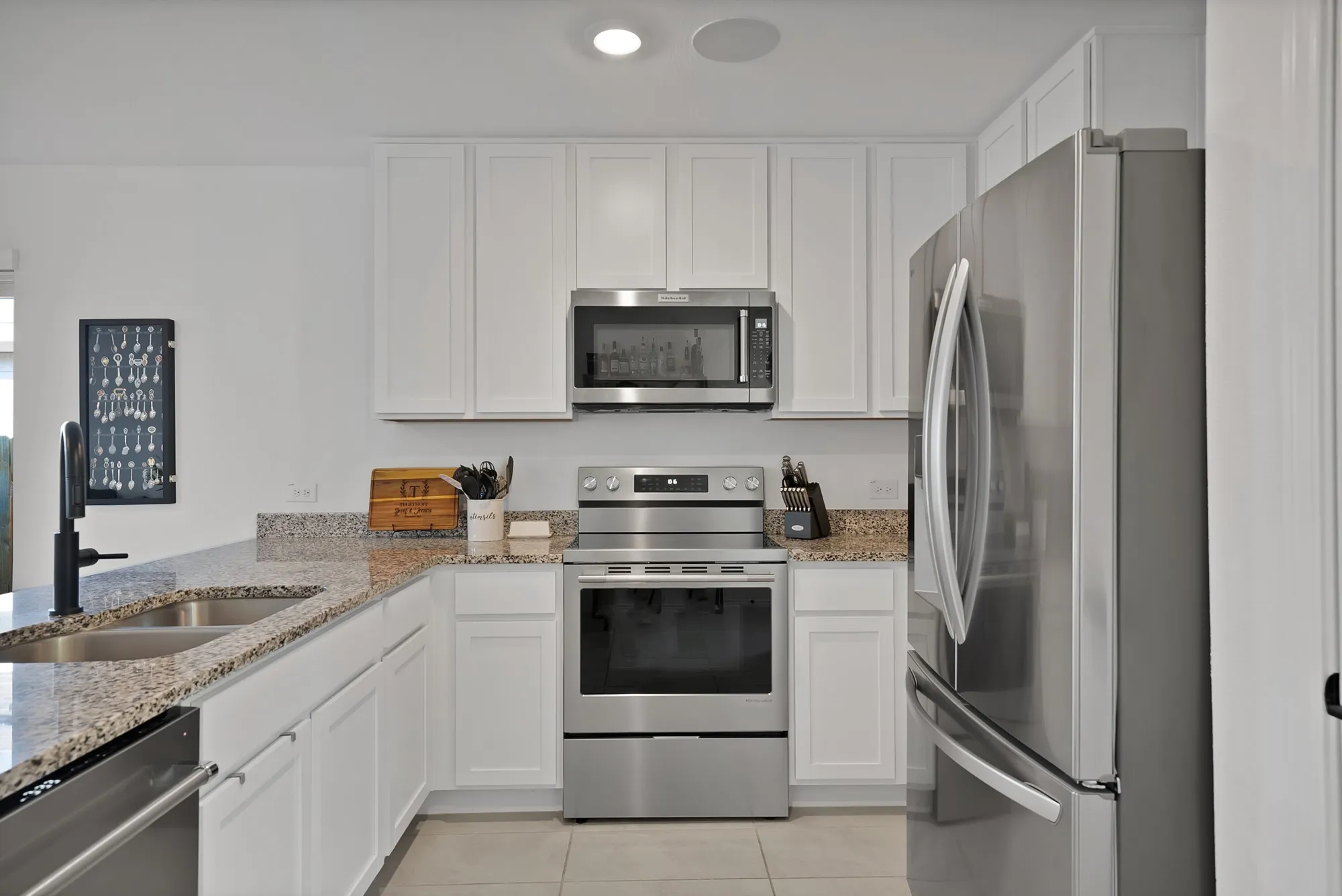 Kitchen featuring white cabinetry, speckled countertops, stainless steel appliances, and a dual basin sink with a matte black faucet