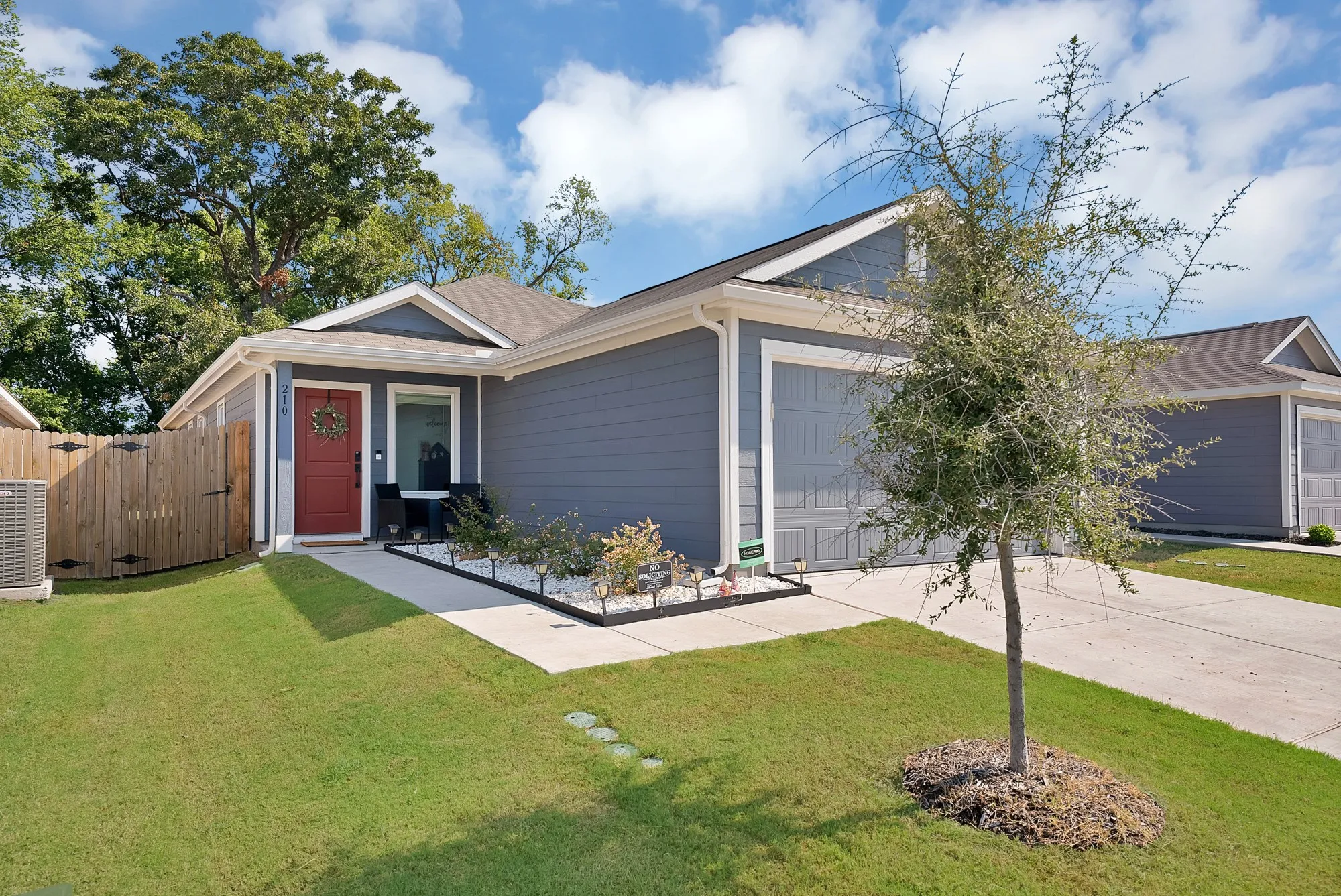 Modern exterior with siding, attached garage, concrete driveway, front walkway, and mature landscaping