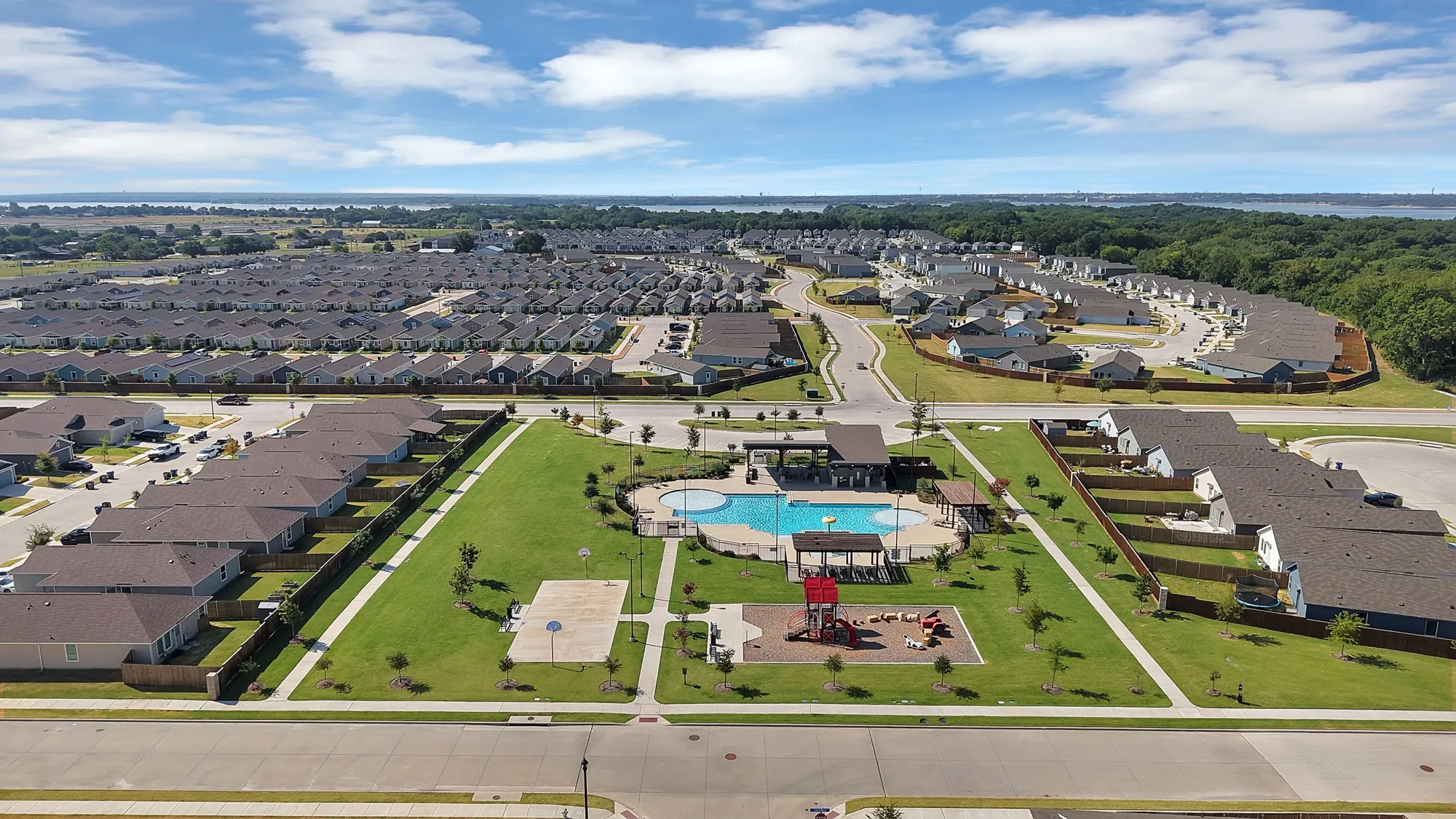 Neighborhood pool with adjacent covered patio, playground area, and basketball court