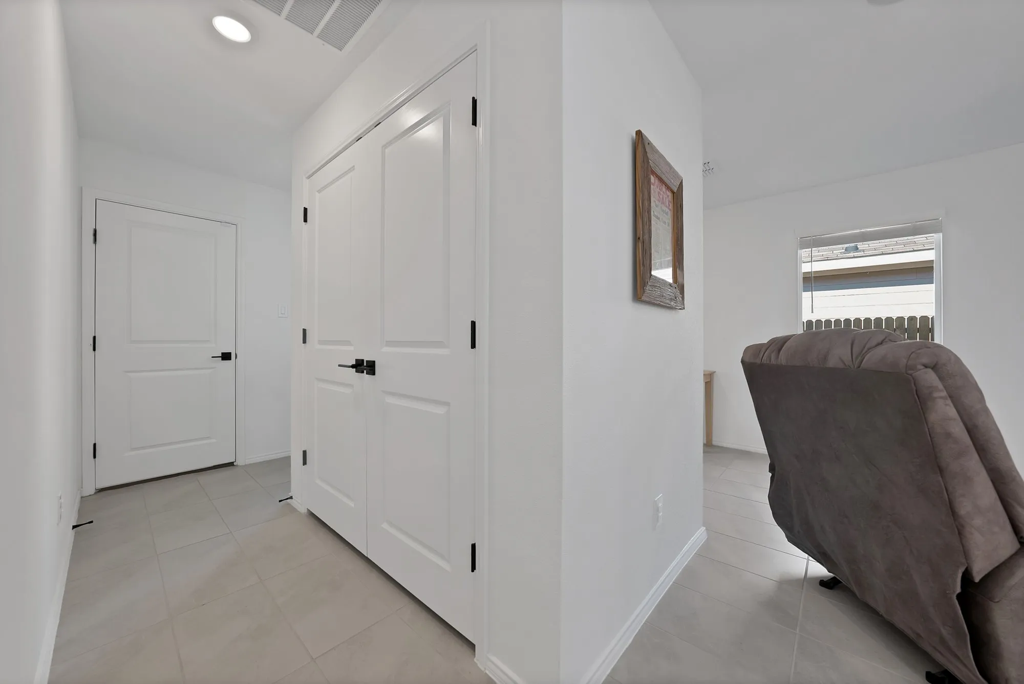 White paneled doors with matte black hardware, recessed ceiling lighting, and light-toned tile flooring