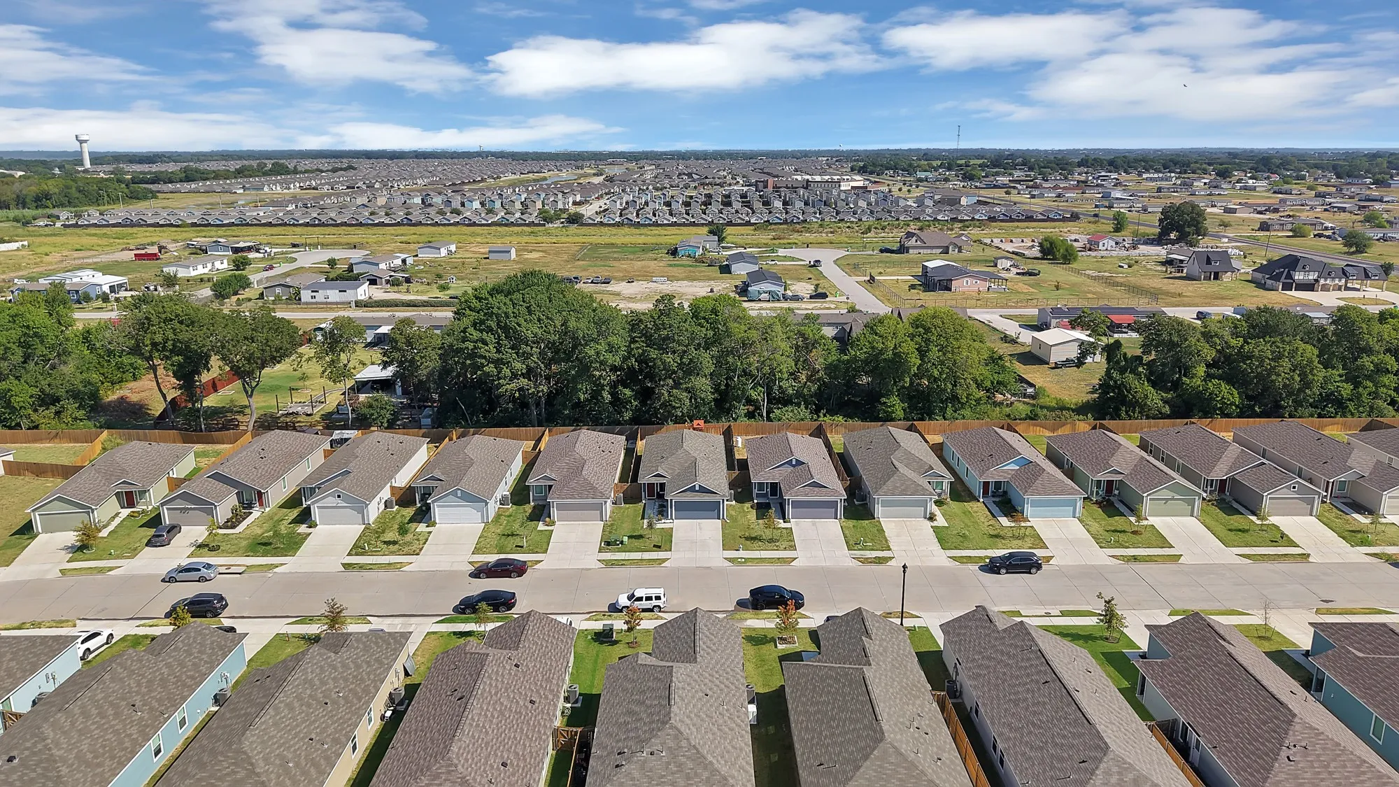 Residential development featuring single-story homes, paved streets, and concrete driveways