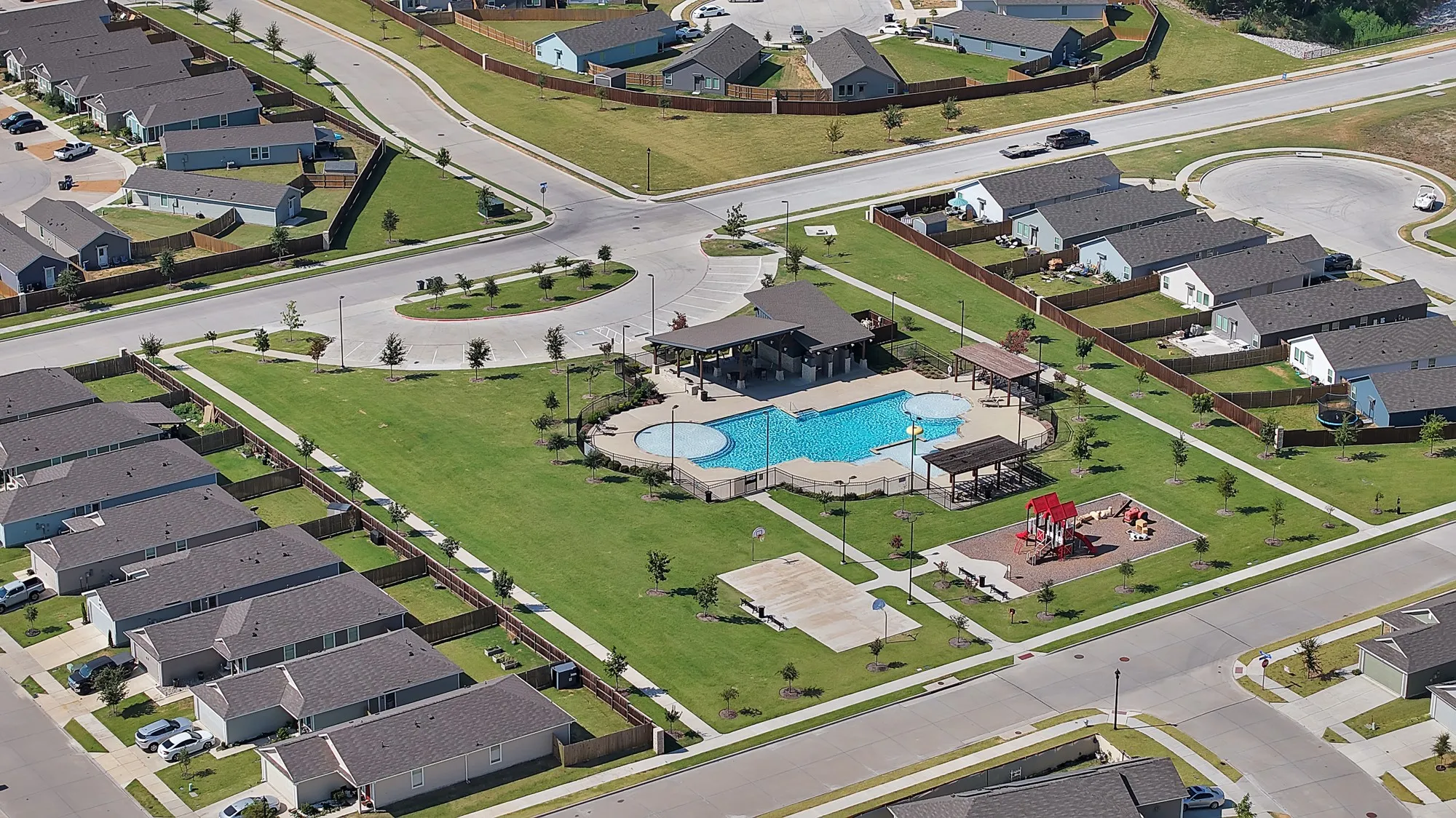 Community recreation area featuring a swimming pool, shaded seating, and a playground