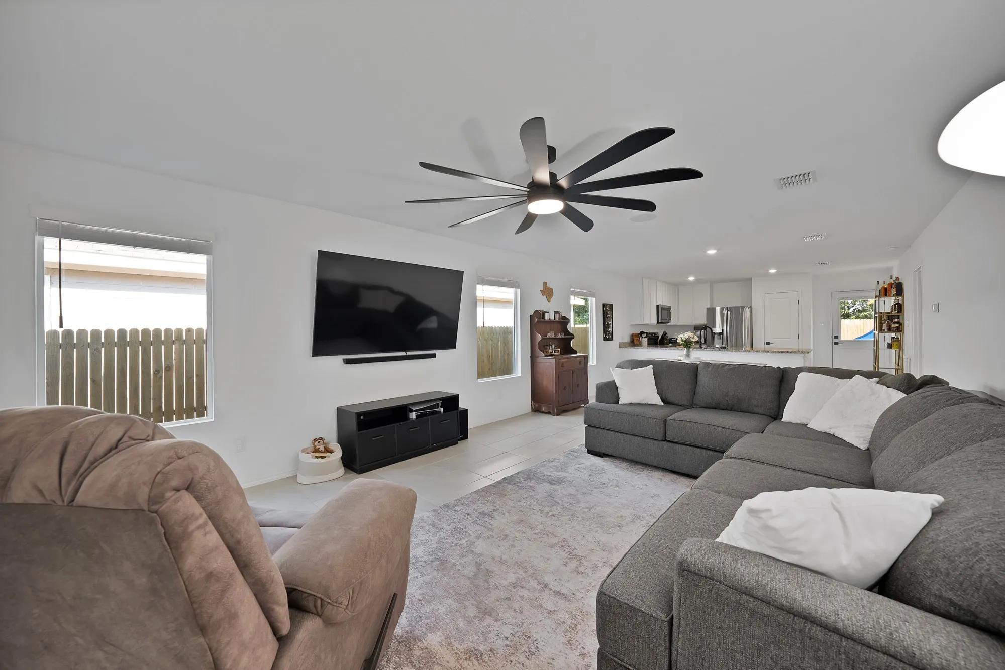 Open-concept living area with light-toned flooring, recessed lighting, and a modern ceiling fan