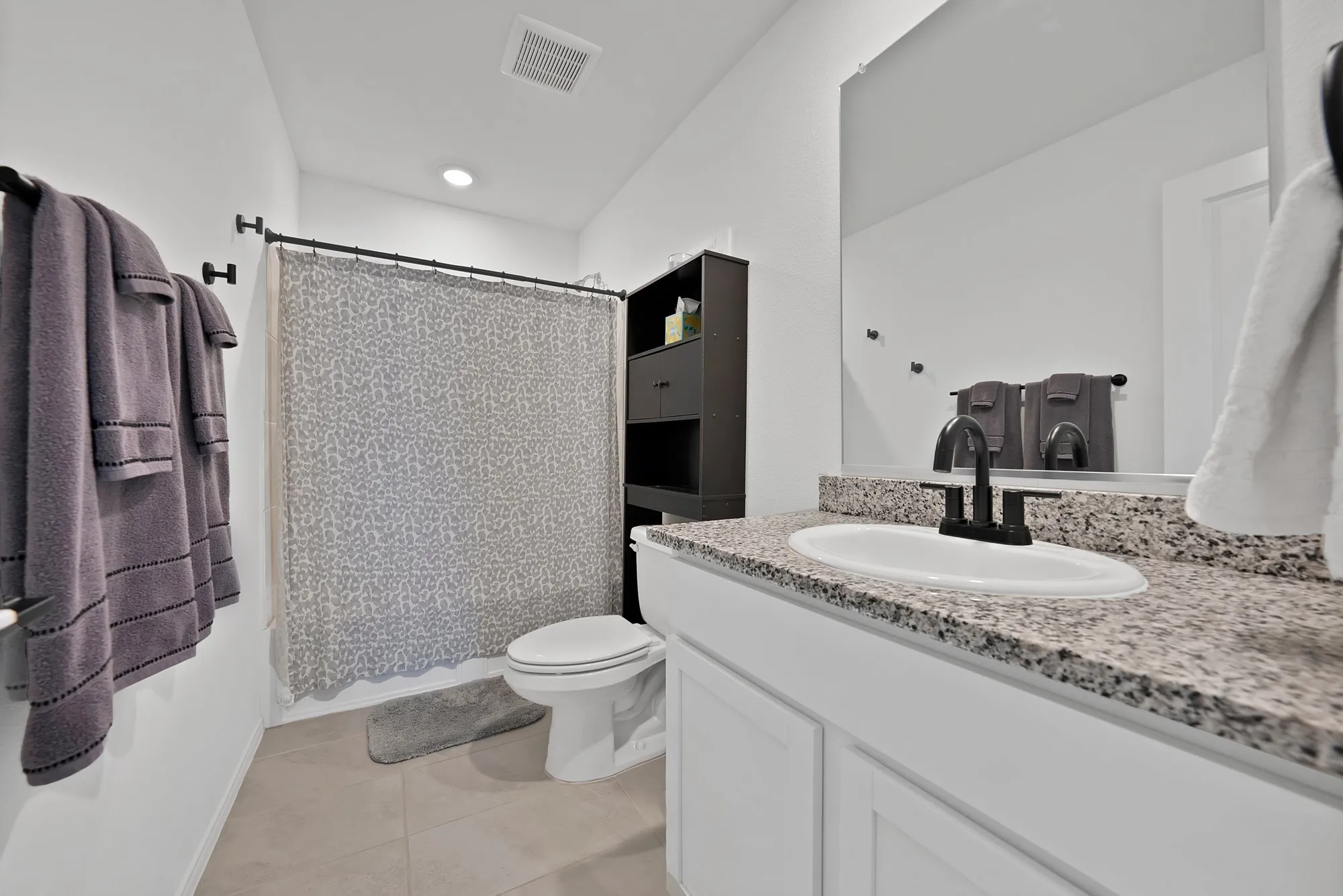 Bathroom featuring a vanity with an undermount sink, speckled countertop, and matte black faucet