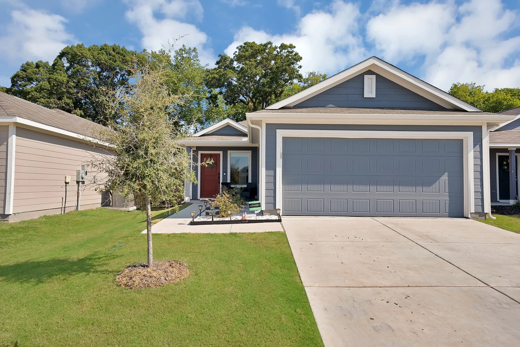 Gable roofline with white trim, blue siding, a two-car garage, and a red front door