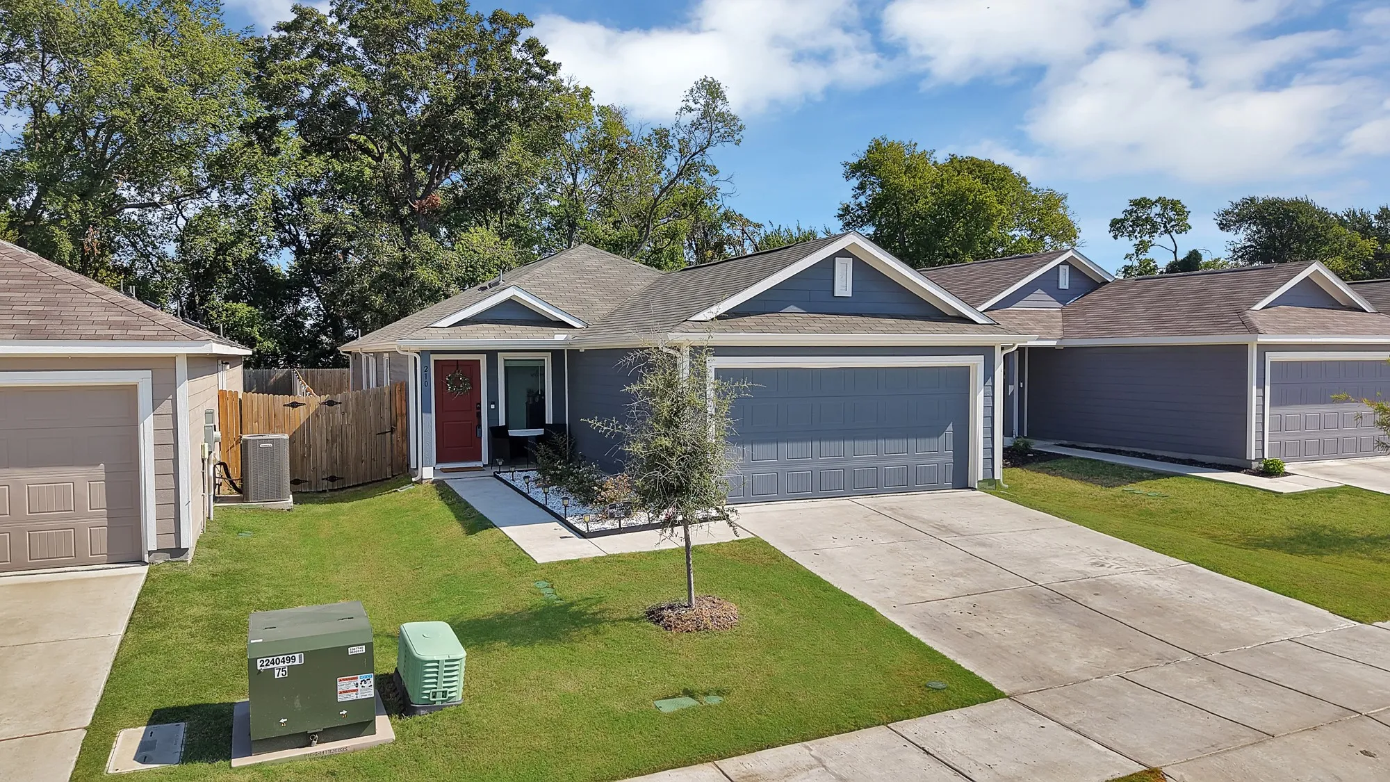 Single-story residence featuring a blue siding exterior, attached garage, and a red entry door
