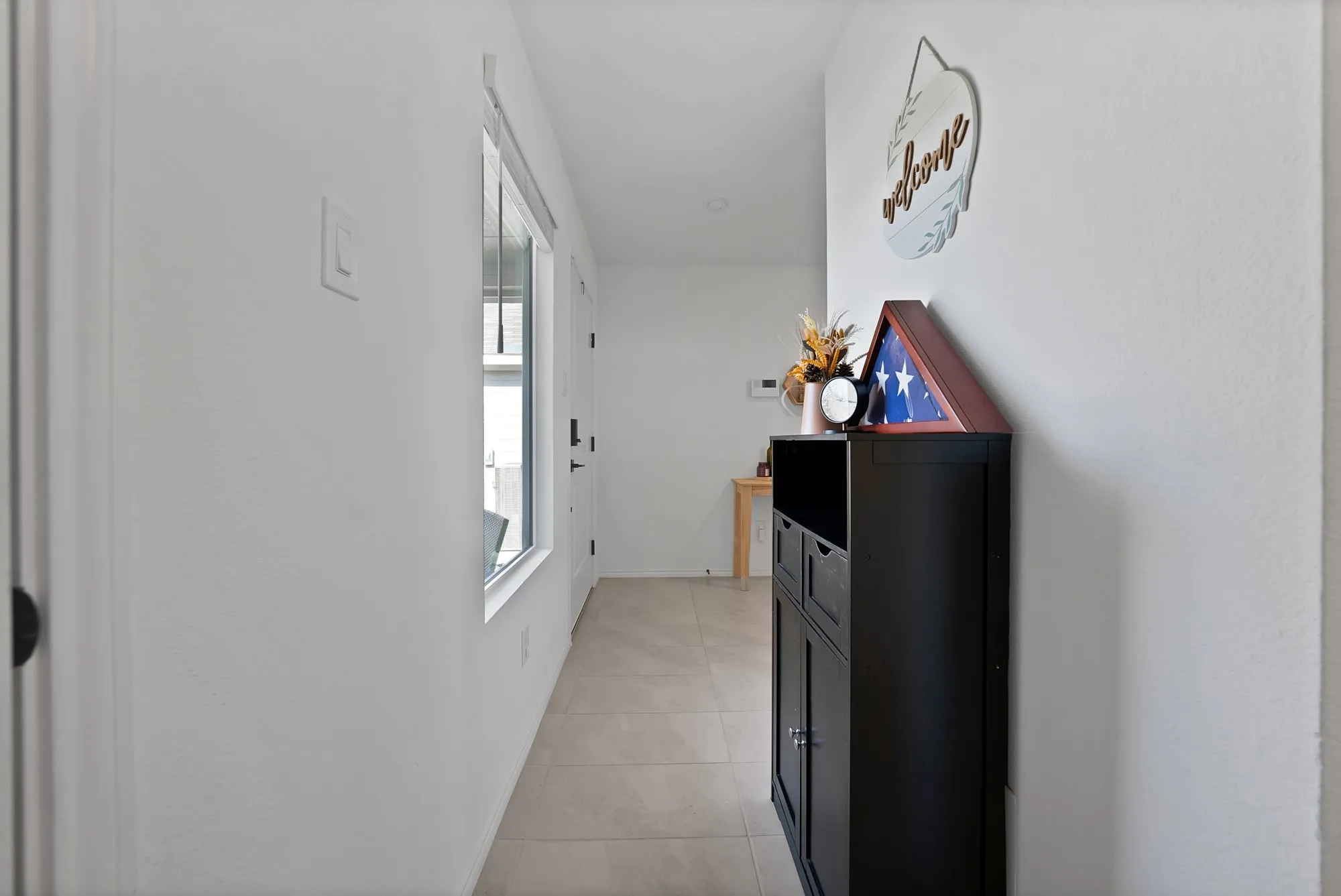 Entryway featuring light-toned tile flooring, a window with white trim, and white walls