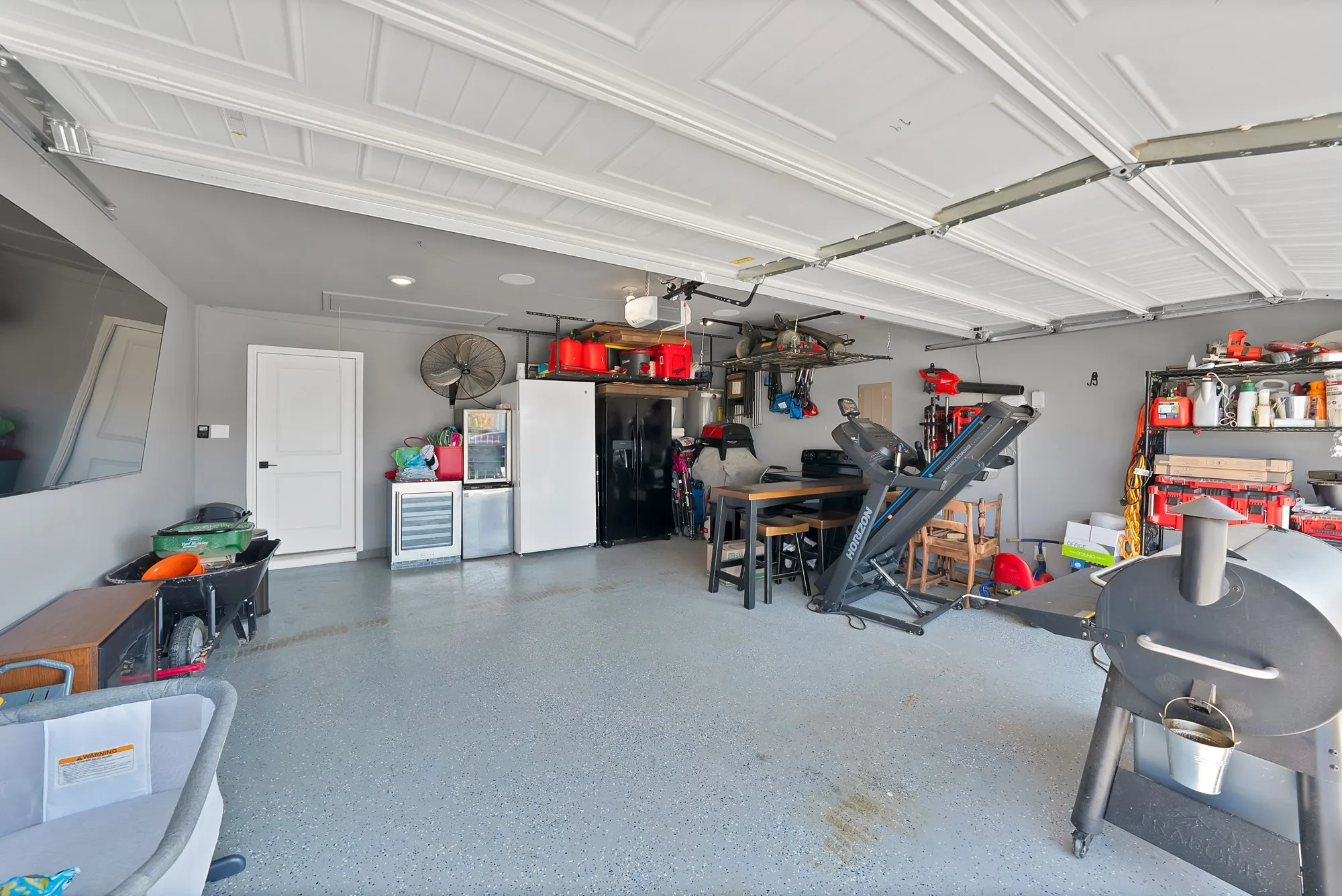 Garage featuring a speckled epoxy floor, overhead storage racks, and wall-mounted shelving