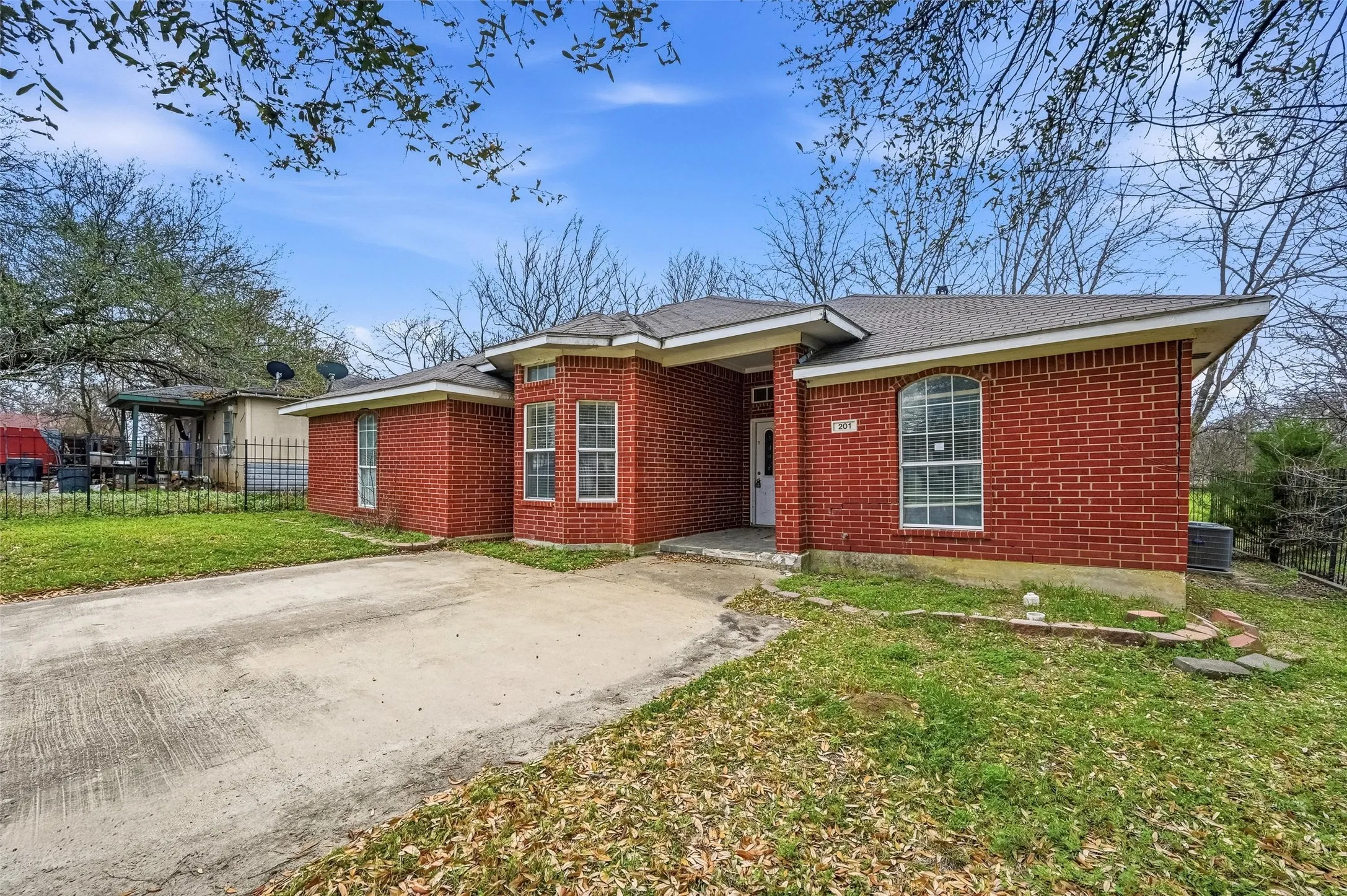Red brick exterior with a multi-paned bay window, arched window, and a concrete driveway