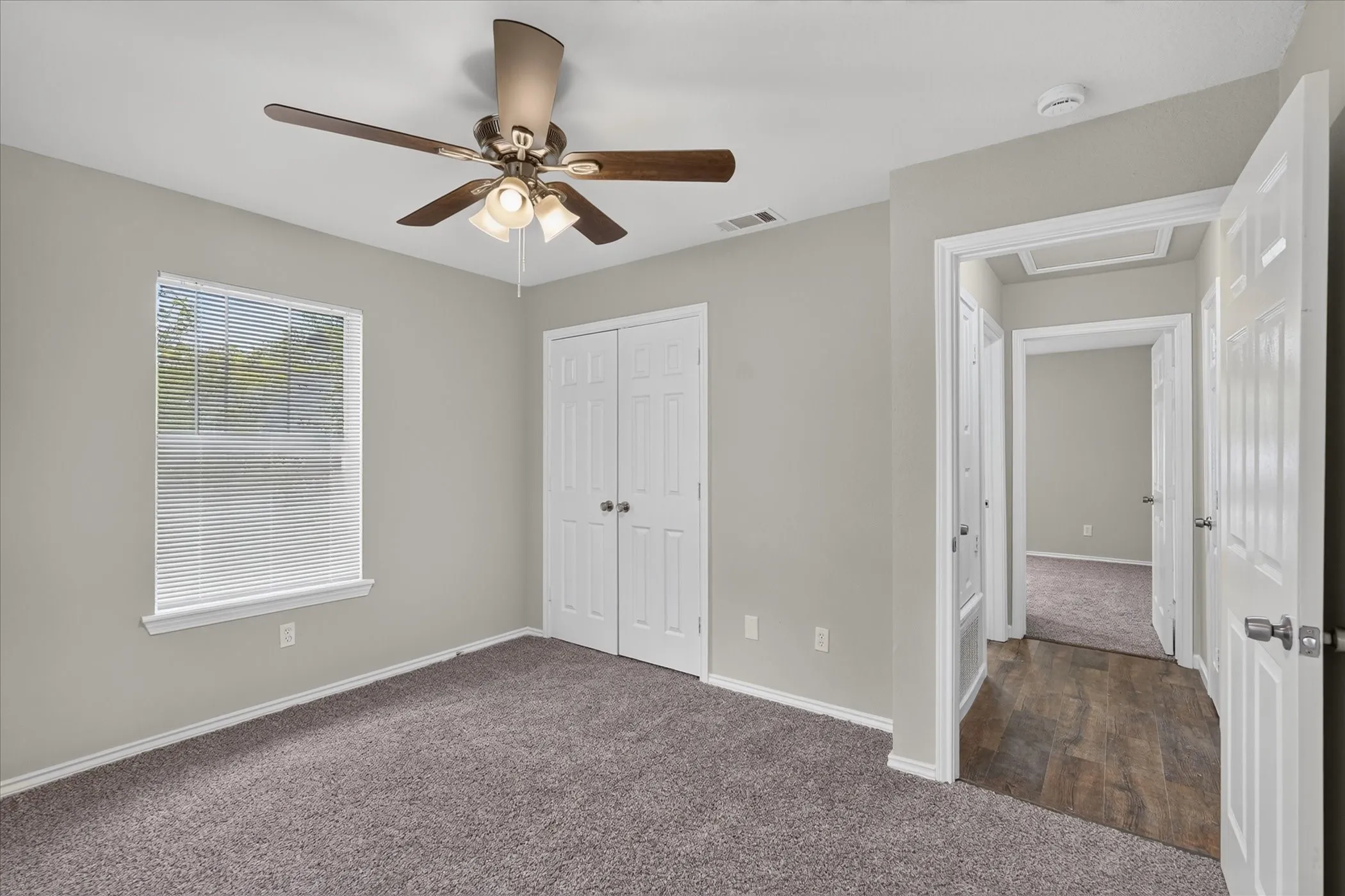 Carpeted room with a ceiling fan light fixture