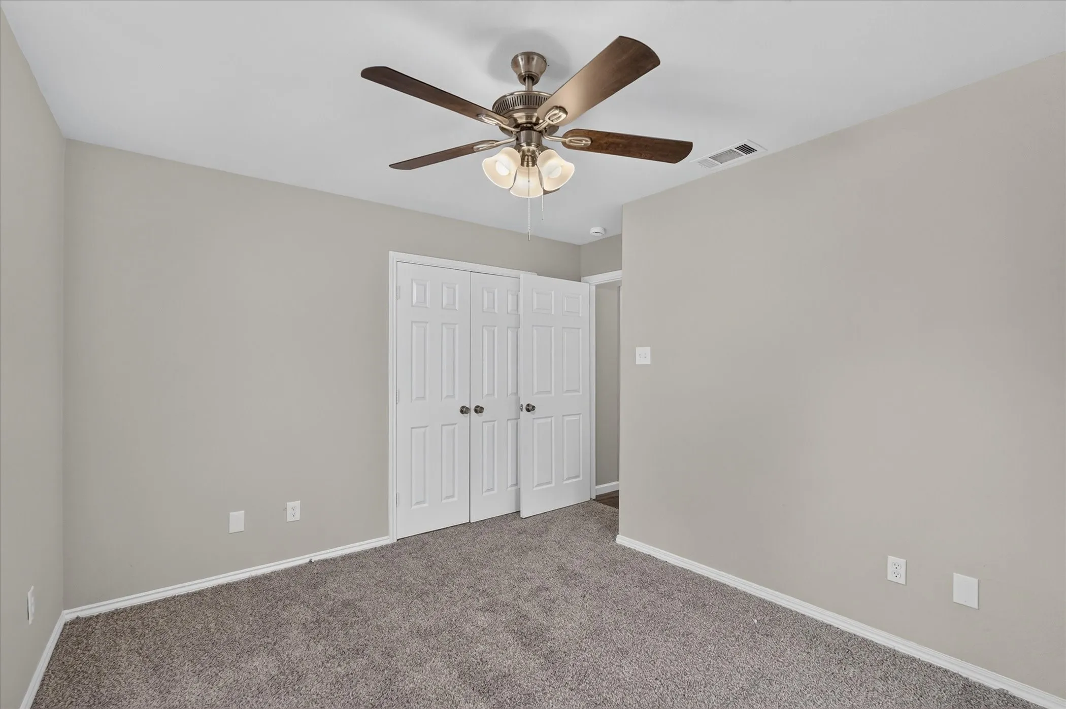 Neutral wall color, carpeted flooring, bi-fold closet doors, and a ceiling fan with integrated lighting