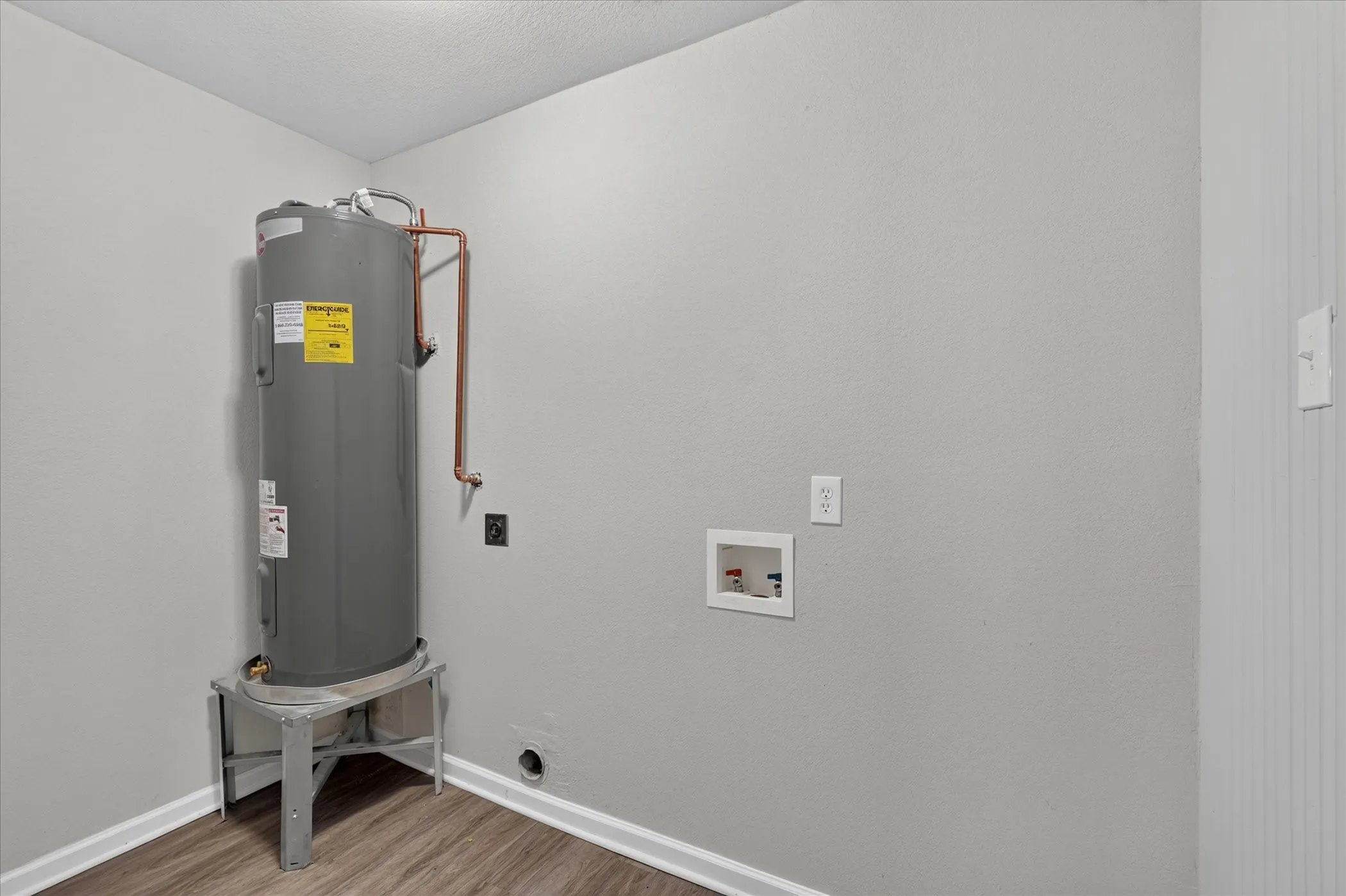 Dedicated utility space with a water heater, laundry hookups, and wood-finish flooring