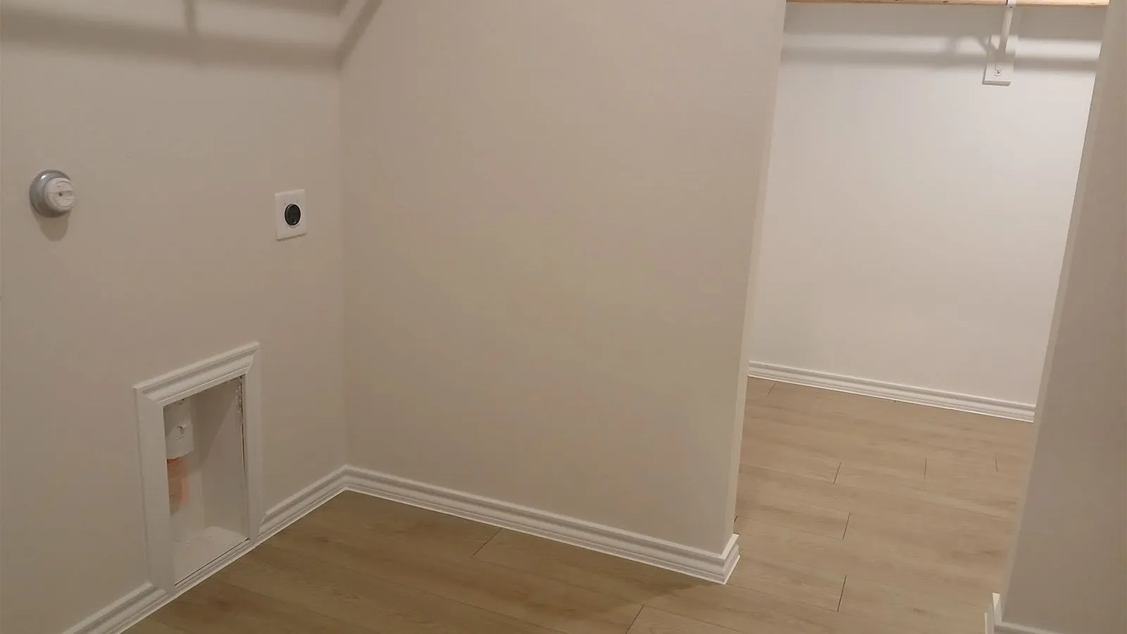 Laundry area featuring light wood-finish flooring, white walls, and built-in shelving