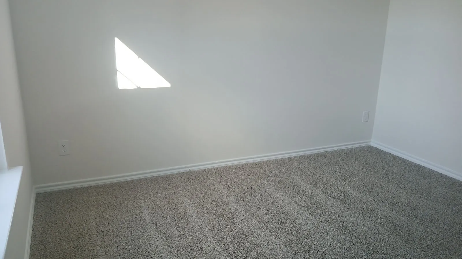 Light gray walls with white trim and gray carpeting